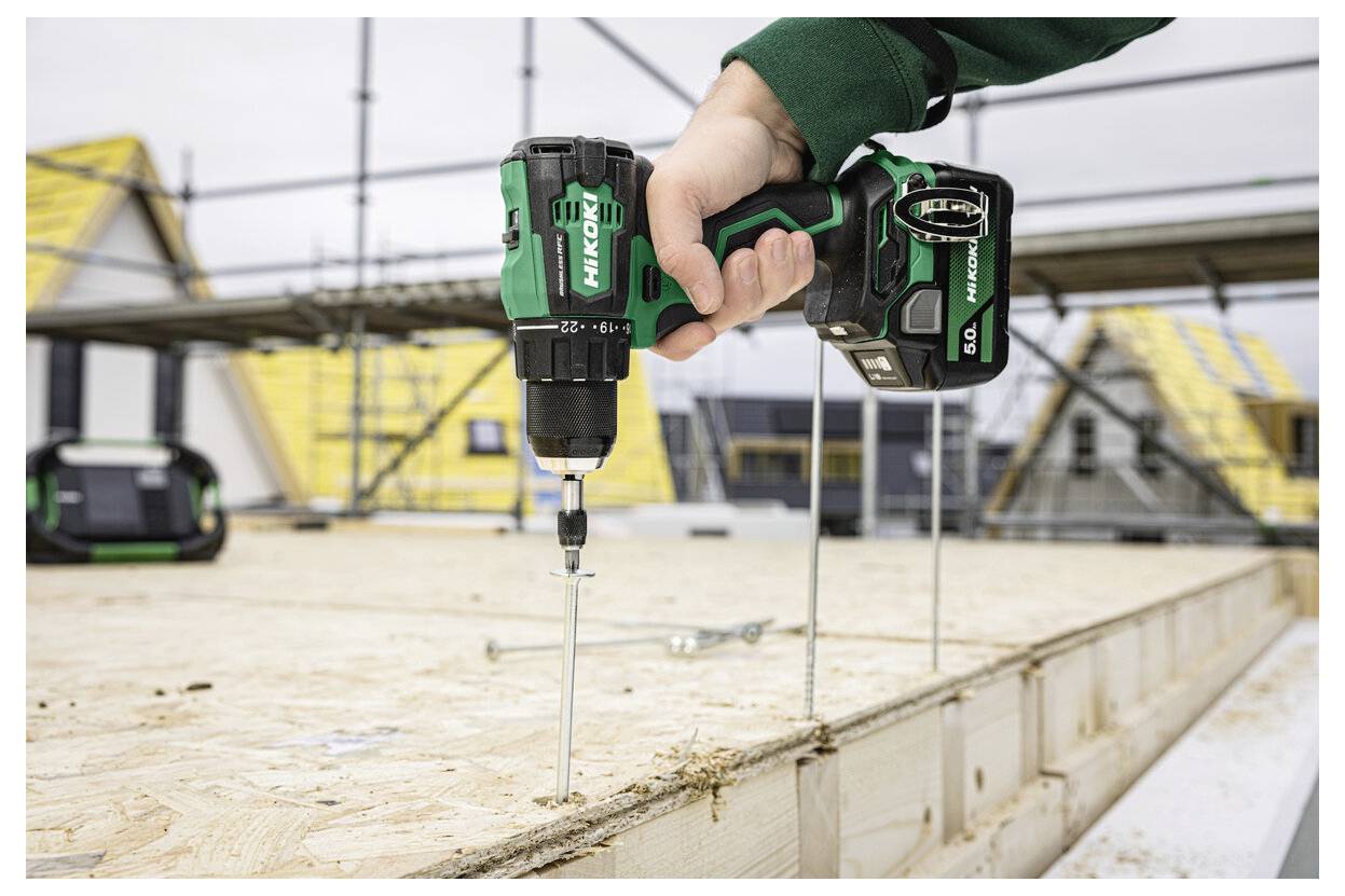 Hand, die einen kabellosen Bohrer verwendet, um Schrauben in ein Holzkonstruktionspanel auf einer Baustelle zu treiben.