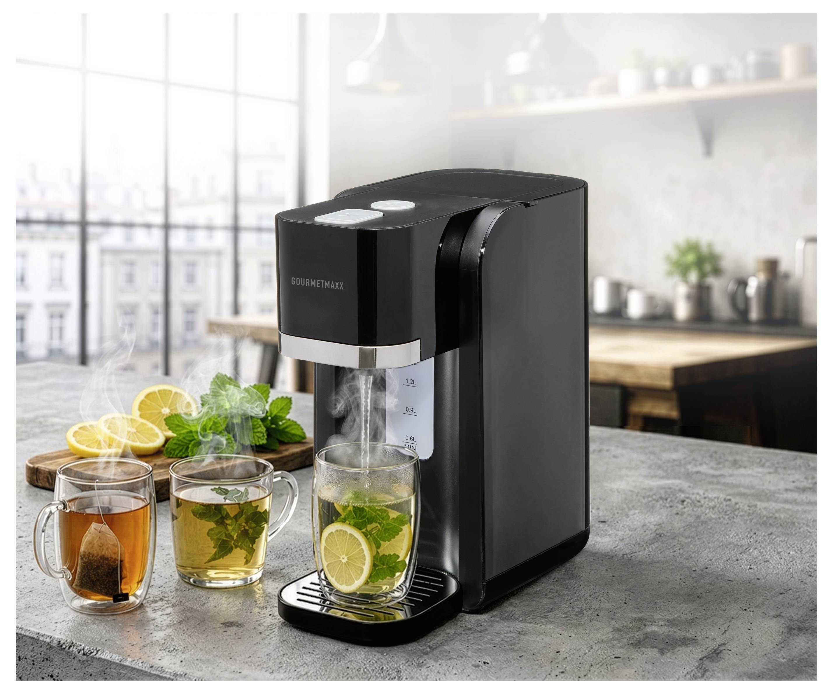 Schwarze Arbeitsplatte Heißwasserspender, der Tee in eine Glastasse mit Zitrone und Minze braut, neben anderen Teetassen und Zitronenscheiben auf einer Küchentheke.