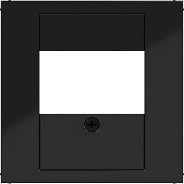 Schwarze Wandplatte mit einer zentralen rechteckigen Öffnung und einer kleinen Schraube, wahrscheinlich eine Lichtschalter- oder Steckdosenabdeckung.