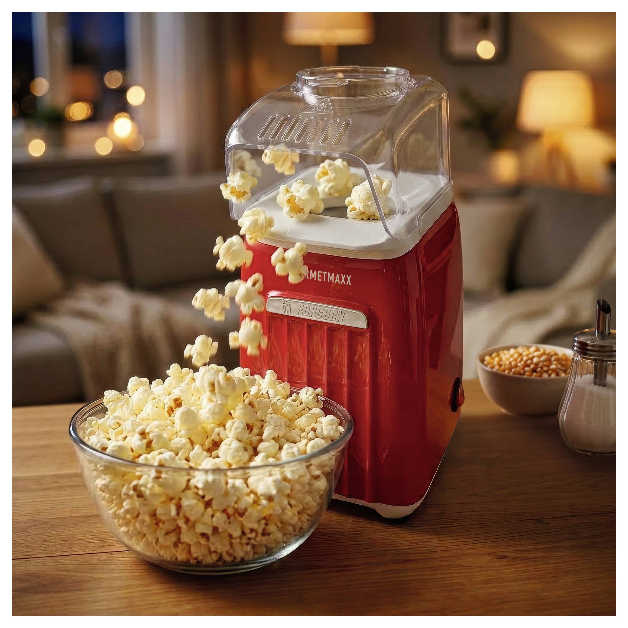 Roter Popcornmaker gießt Popcorn in eine Schüssel auf einem Holztisch in einem gemütlichen Wohnzimmer.