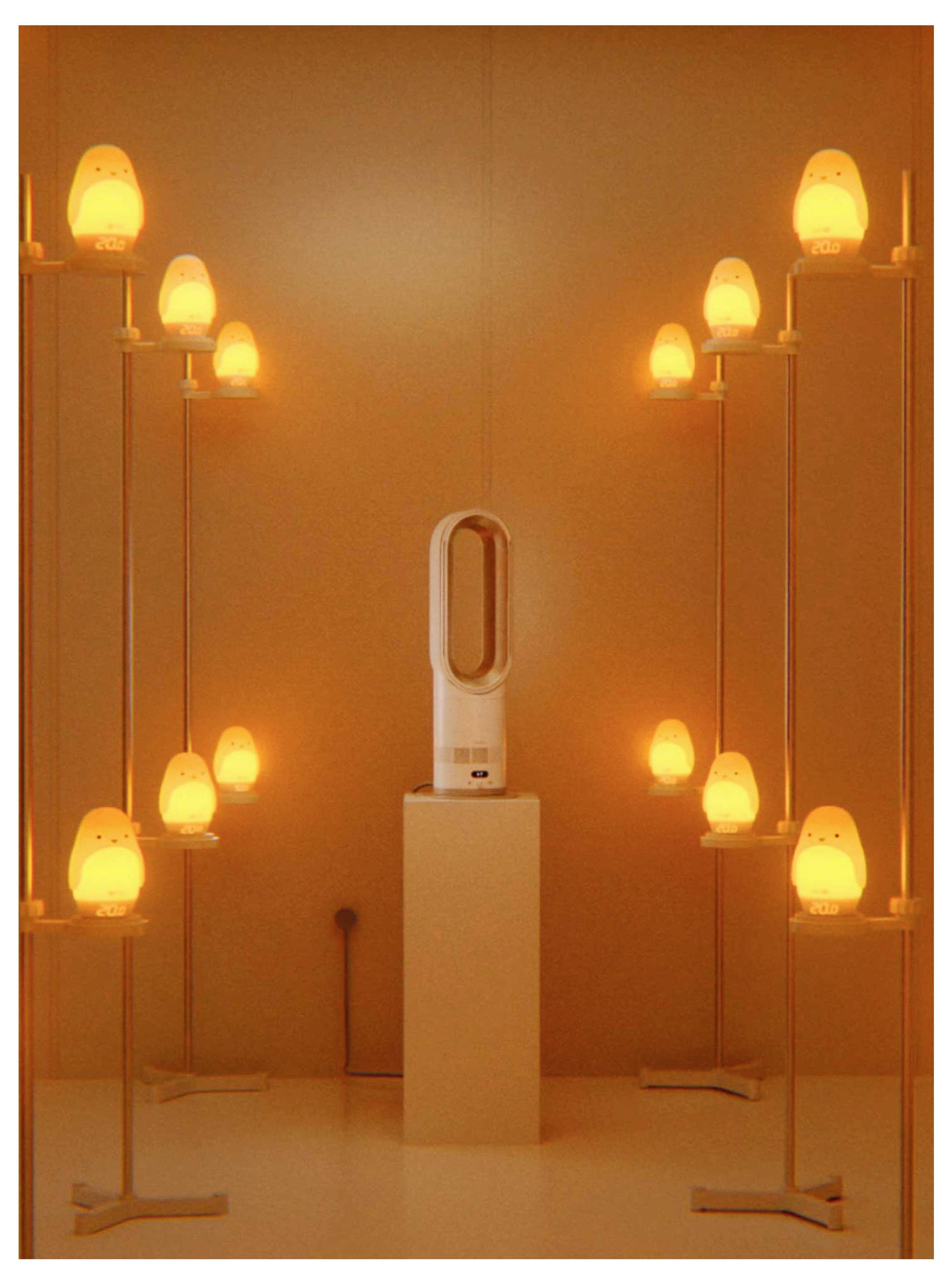Ein weißer blattloser Turmventilator auf einem Standfuß, umgeben von leuchtenden orangefarbenen lampenähnlichen Lichtern in einem warmen Raum.