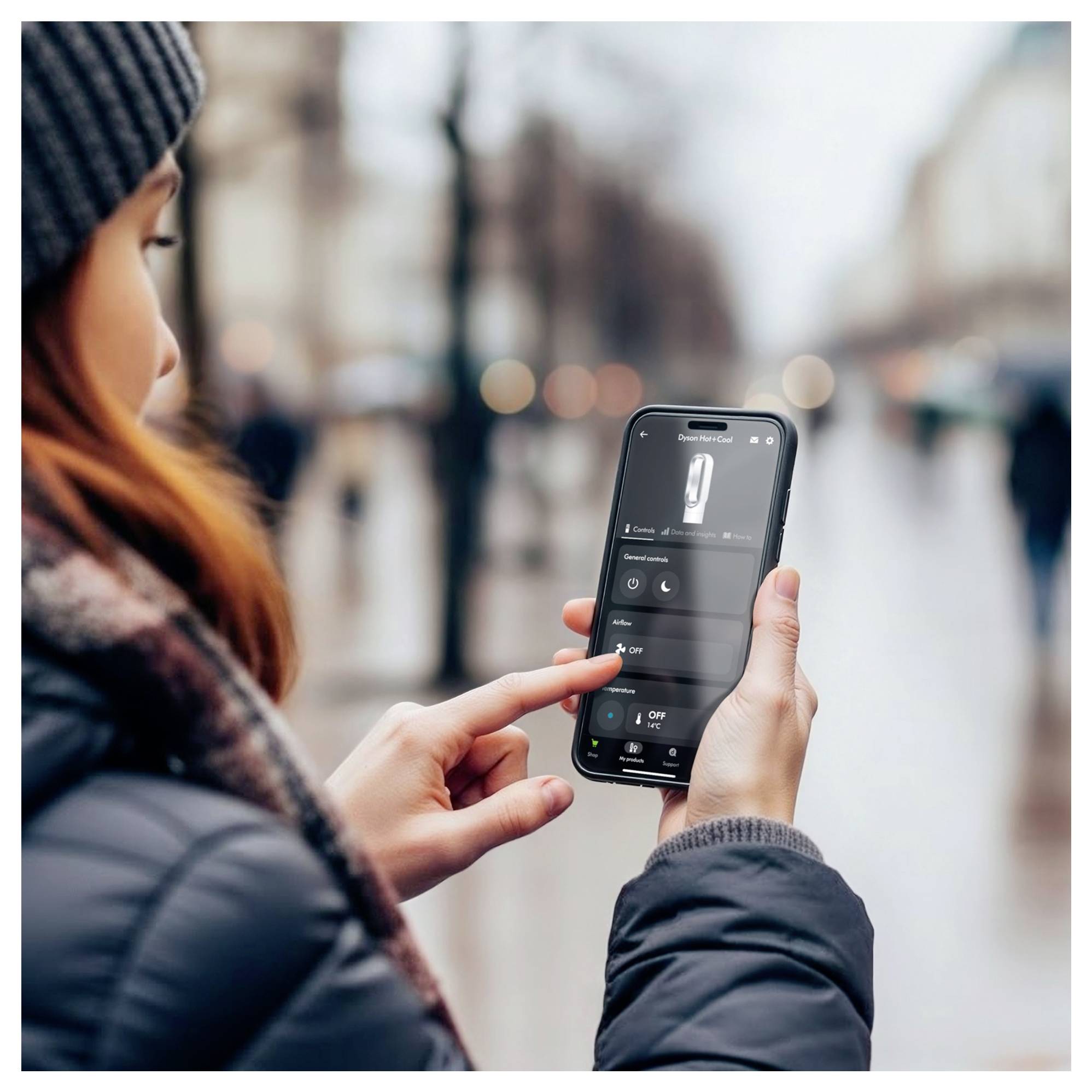Person nutzt ein Smartphone zur Steuerung einer verbundenen Geräte-App im Freien auf einer Stadtstraße.