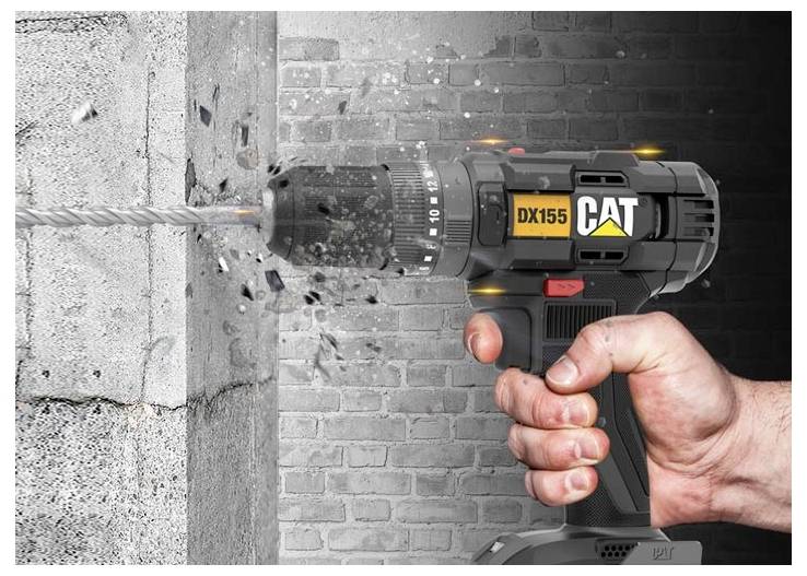 Eine Hand bedient einen CAT DX155 kabellosen Bohrer, der in eine Betonwand bohrt, wobei Staub und Schutt vom Bohrer wegfliegen.