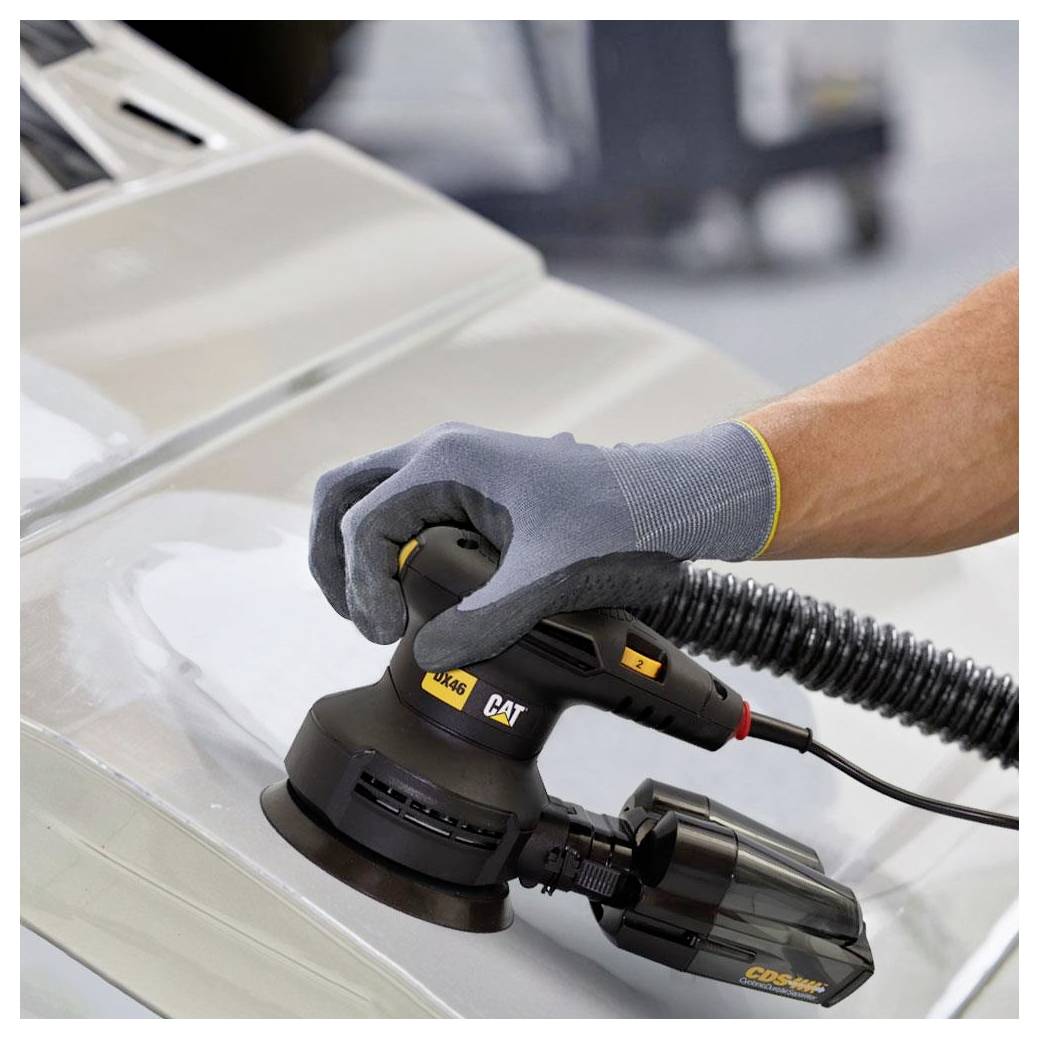 Behandschuhte Hand, die einen CAT-Elektroschleiferl/Polierer auf einem Fahrzeugkarosserieteil verwendet, wahrscheinlich zur Autoreparatur oder Oberflächenveredelung.