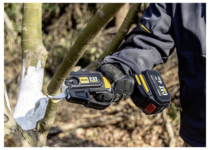 Handschuhtragender Arbeiter benutzt eine kabellose CAT-Astschneidesäge zum Schneiden eines Baumasts im Freien.