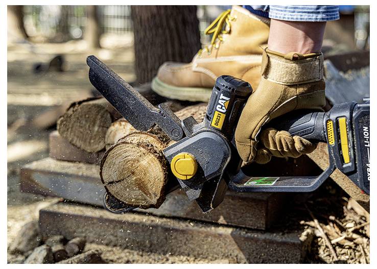 Person mit Handschuhen, die eine batteriebetriebene Kettensäge verwendet, um einen Baumstamm auf gestapeltem Holz im Freien zu schneiden.