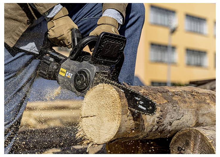 Arbeiter, der mit einer Kettensäge einen großen Baumstamm im Freien durchsägt, wobei Holzspäne umherfliegen.