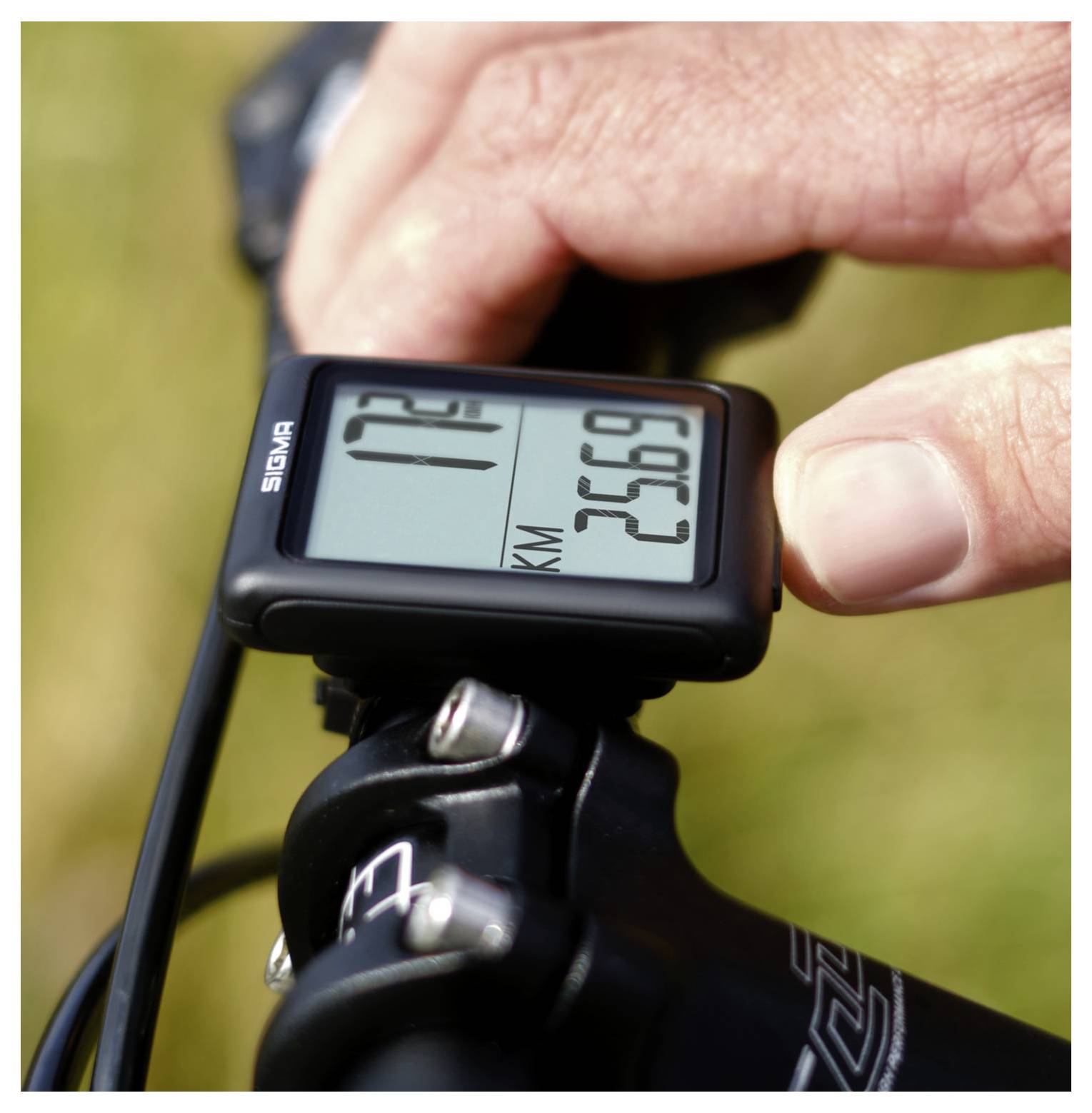 Nahaufnahme eines Fahrrad-Lenker-GPS-Computers mit Fahrtdaten, einschließlich Geschwindigkeit und Entfernung, während eine Hand das Gerät einstellt.