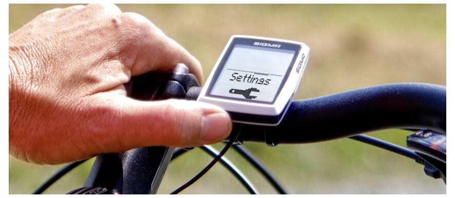 Hand passt einen Fahrrad-Lenkercomputer an, auf dem Bildschirm 
