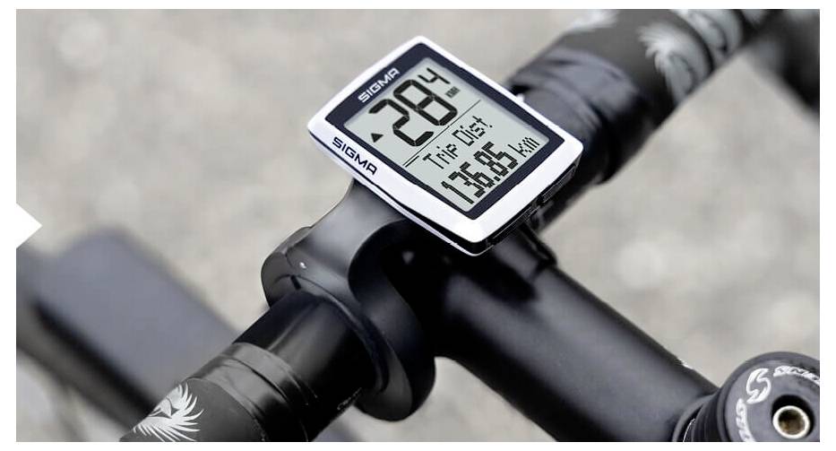 Nahaufnahme eines Fahrradvorbaus mit einem Sigma-Fahrradcomputer, der 28°C und eine Fahrstrecke von 75,85 km anzeigt.