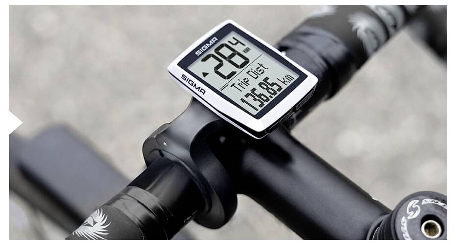 Nahaufnahme eines Fahrradlenkers mit einem Sigma-Fahrradcomputer, der eine Temperatur von 28°, Fahrstrecke 75,65 km und eine Geschwindigkeit von 0 km/h anzeigt.