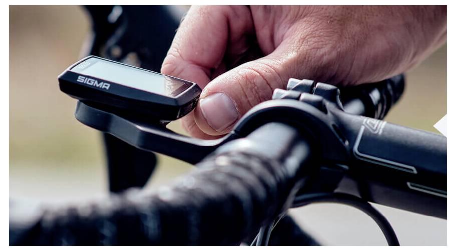 Nahaufnahme der Hand eines Radfahrers beim Montieren eines Sigma-Fahrradcomputers am Lenker.
