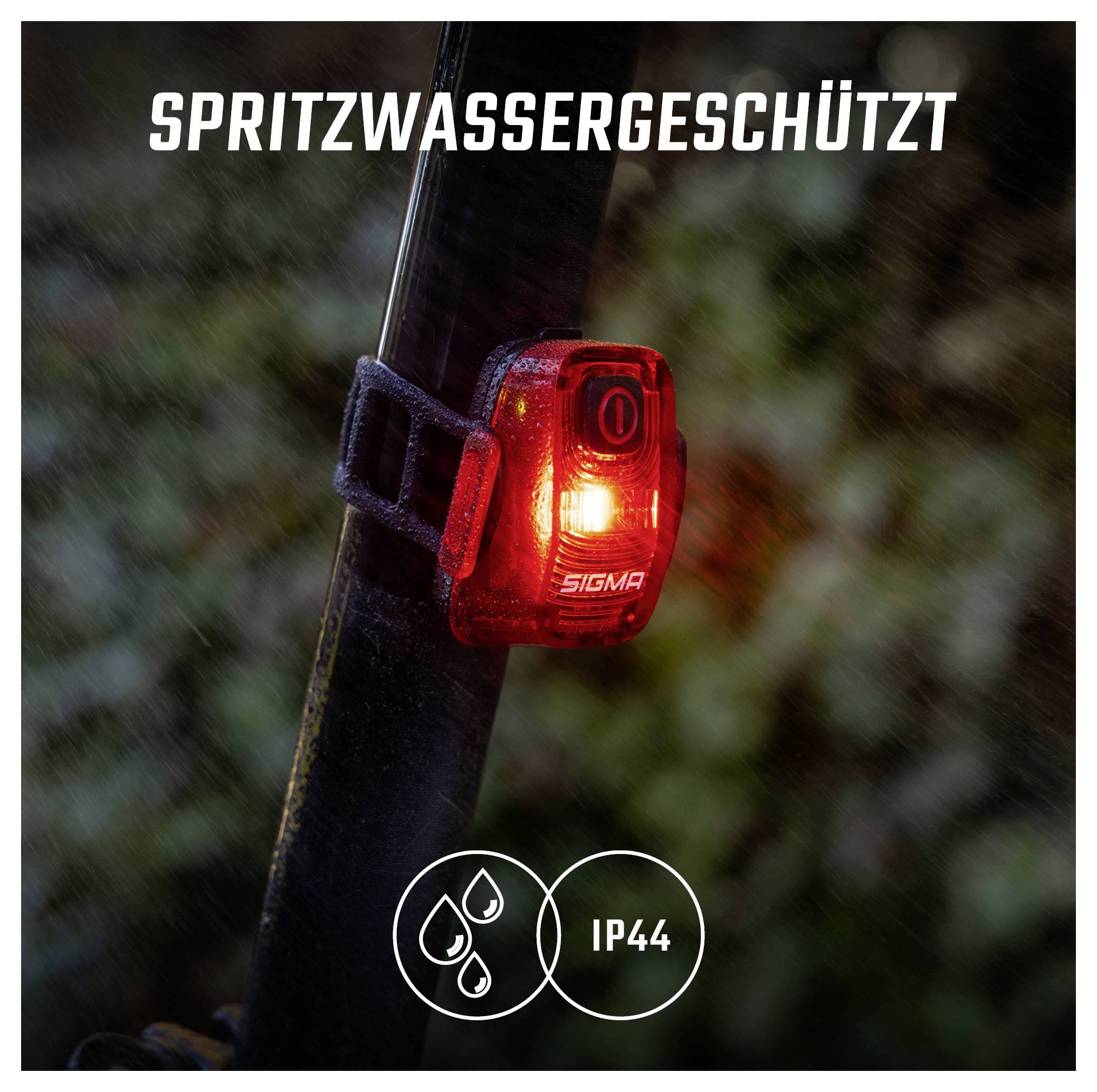 Rote Fahrradlampe am Sattelrohr leuchtet im Regen; Text 'SPRITZWASSERGESCHÜTZT' und Symbol 'IP44' zeigen Spritzwasserschutz.