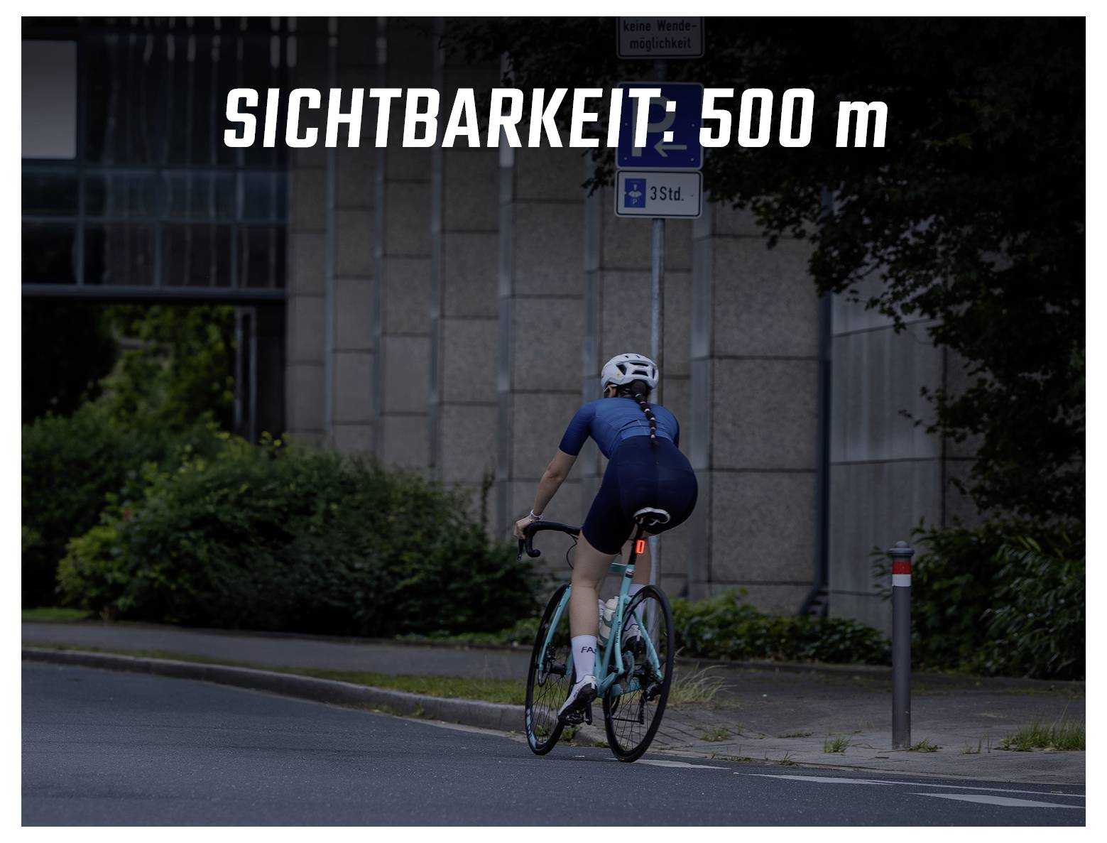 Radfahrerin in dunkler Straße; Einblendung 'SICHTBARKEIT: 500 m' warnt vor schlechter Sichtbarkeit.