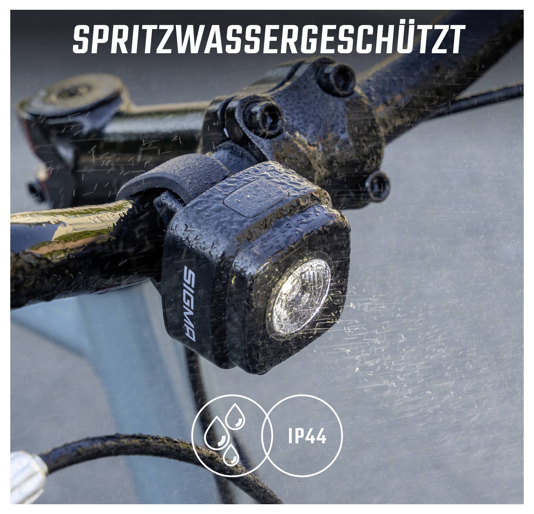 Spritzwassergeschützte Fahrradlampe mit der Aufschrift 'SPRITZWASSERGESCHÜTZT' und IP44-Symbol; wird unter Wasserstrahlen gezeigt.
