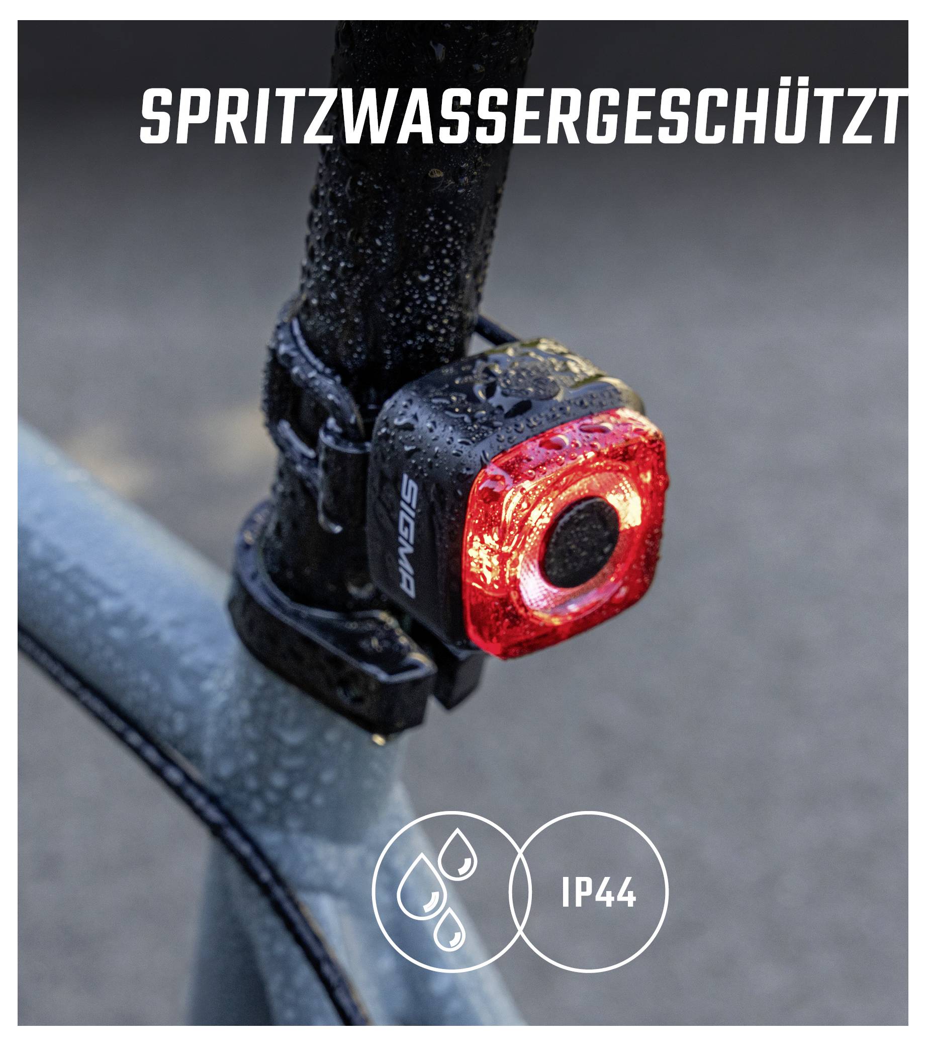 Nahaufnahme eines roten Fahrrad-Rücklichts mit Tropfen; Text 'SPRITZWASSERGESCHÜTZT' und Symbol 'IP44' zeigen den wetterfesten Schutz.