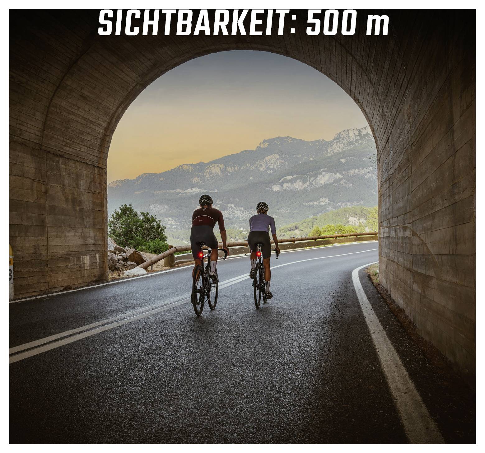 Zwei Radfahrer fahren durch einen Tunnel auf einer kurvenreichen Straße; oben steht 'SICHTBARKEIT: 500 m'.