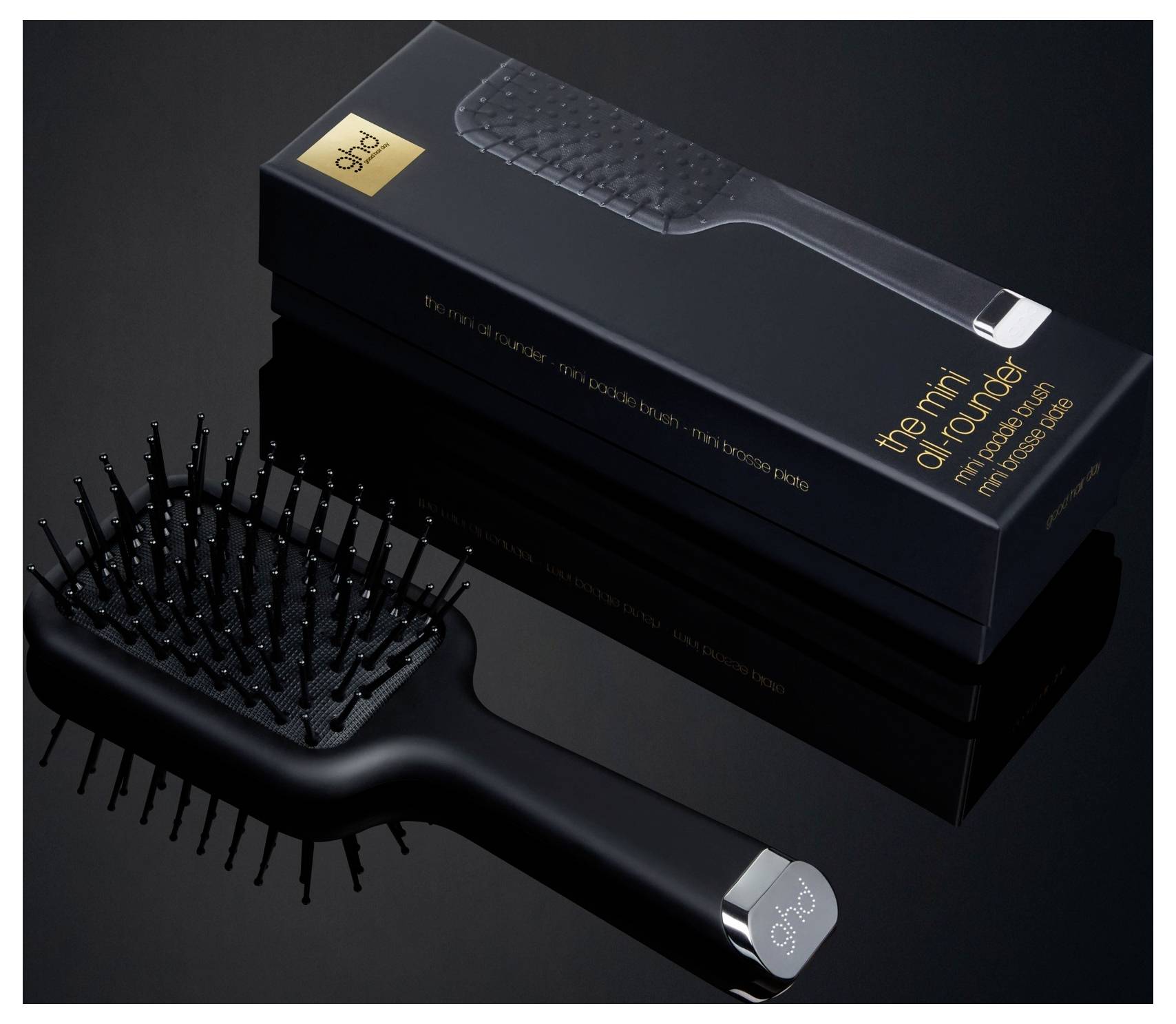Schwarze Haarbürste mit metallspitzigen Borsten, die neben ihrer verpackten Verpackung gezeigt wird, mit der Aufschrift „the mini detangler