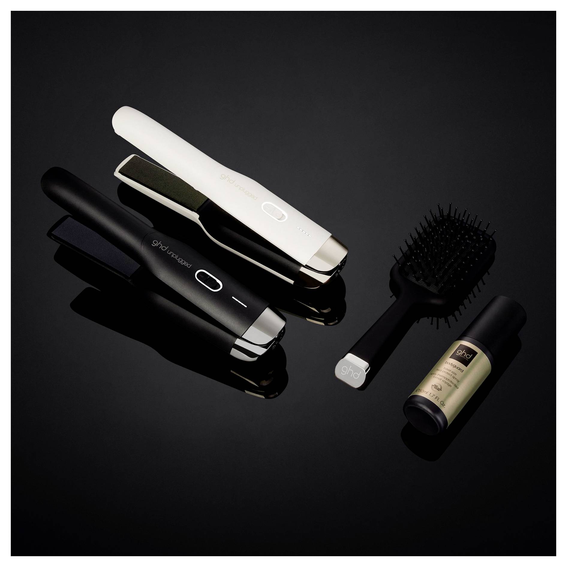 Drei Haarstyling-Werkzeuge auf schwarzem Hintergrund: zwei Glätteisen und eines in Weiß, plus eine Haarbürste und eine Styling-Sprayflasche.