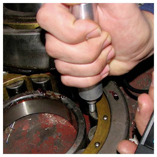 Nahaufnahme von Händen, die ein tragbares Werkzeug verwenden, um eine Komponente in einem mechanischen Gerät festzuziehen oder anzupassen.