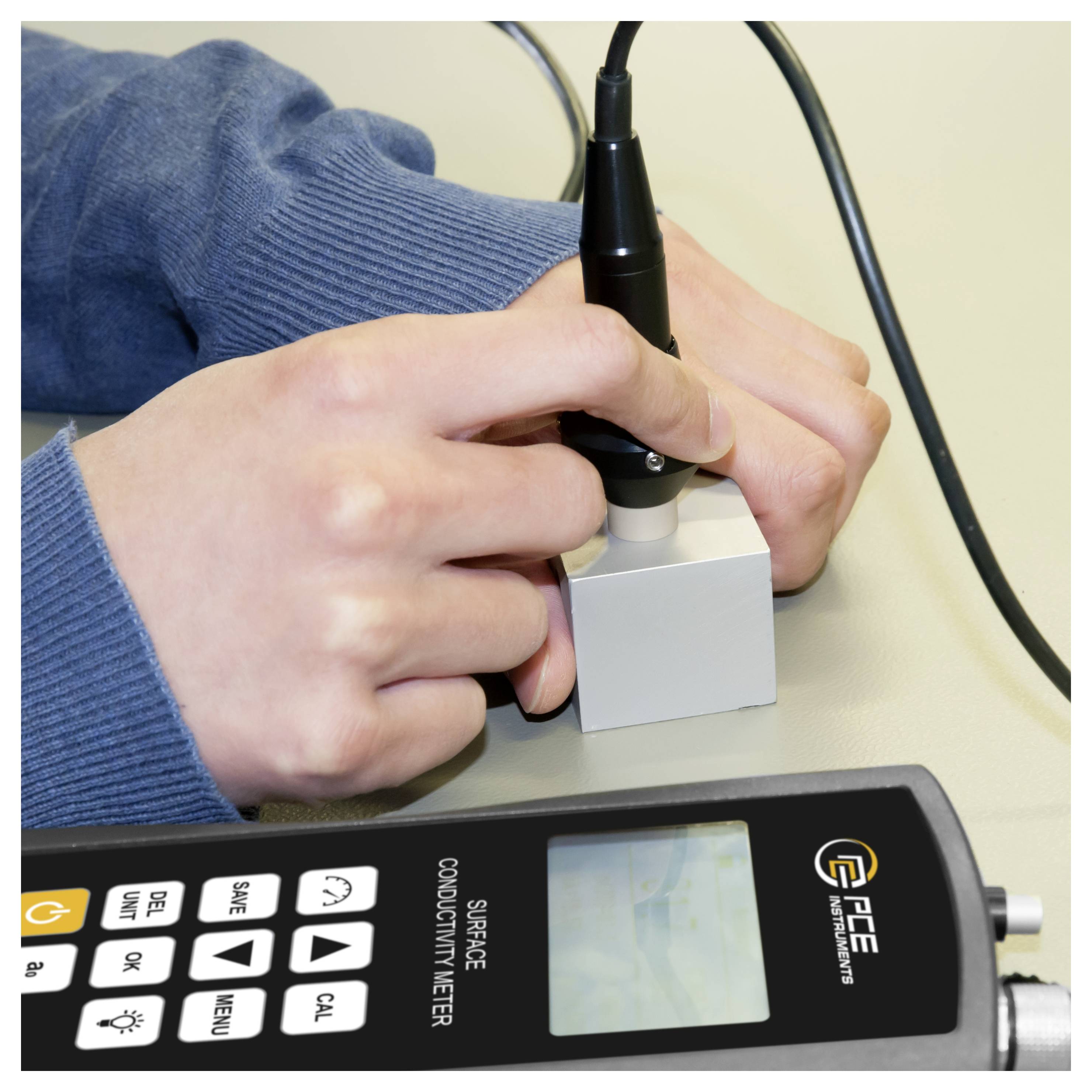 Hände, die eine Sonde auf einem Oberflächenleitfähigkeitsmessgerät mit digitalem Display und Steuertasten verwenden.