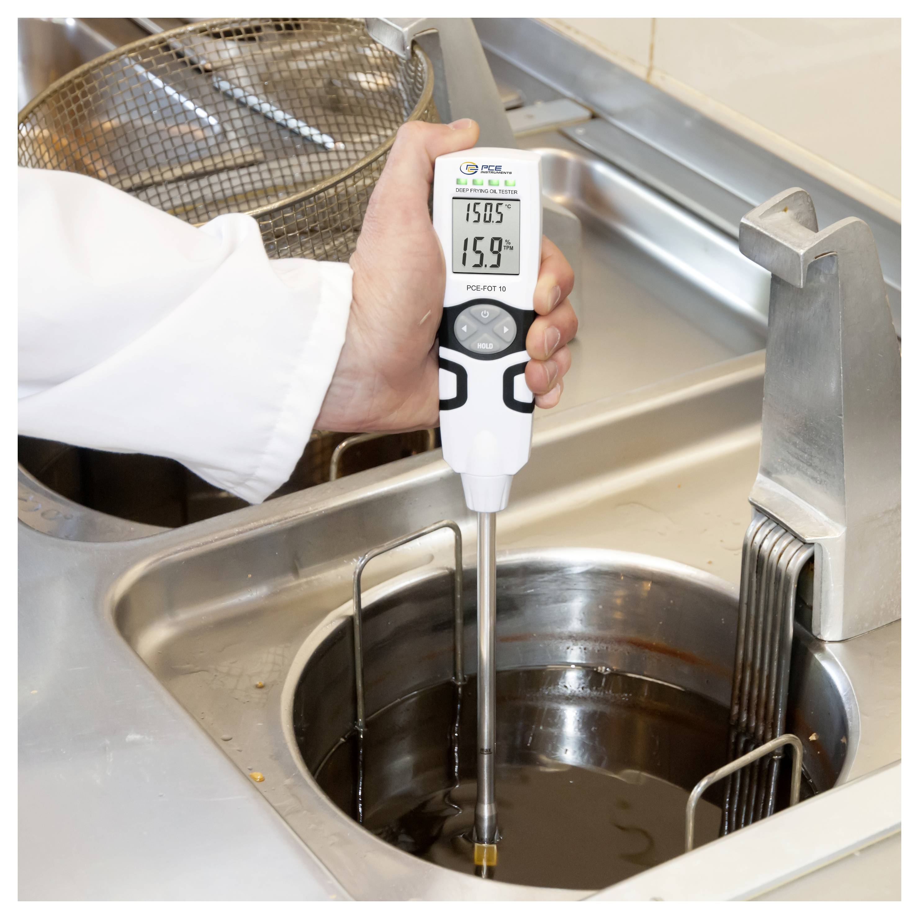 Person, die mit einem digitalen Sondthermometer die Temperatur von heißem Öl in einer gewerblichen Fritteuse misst.