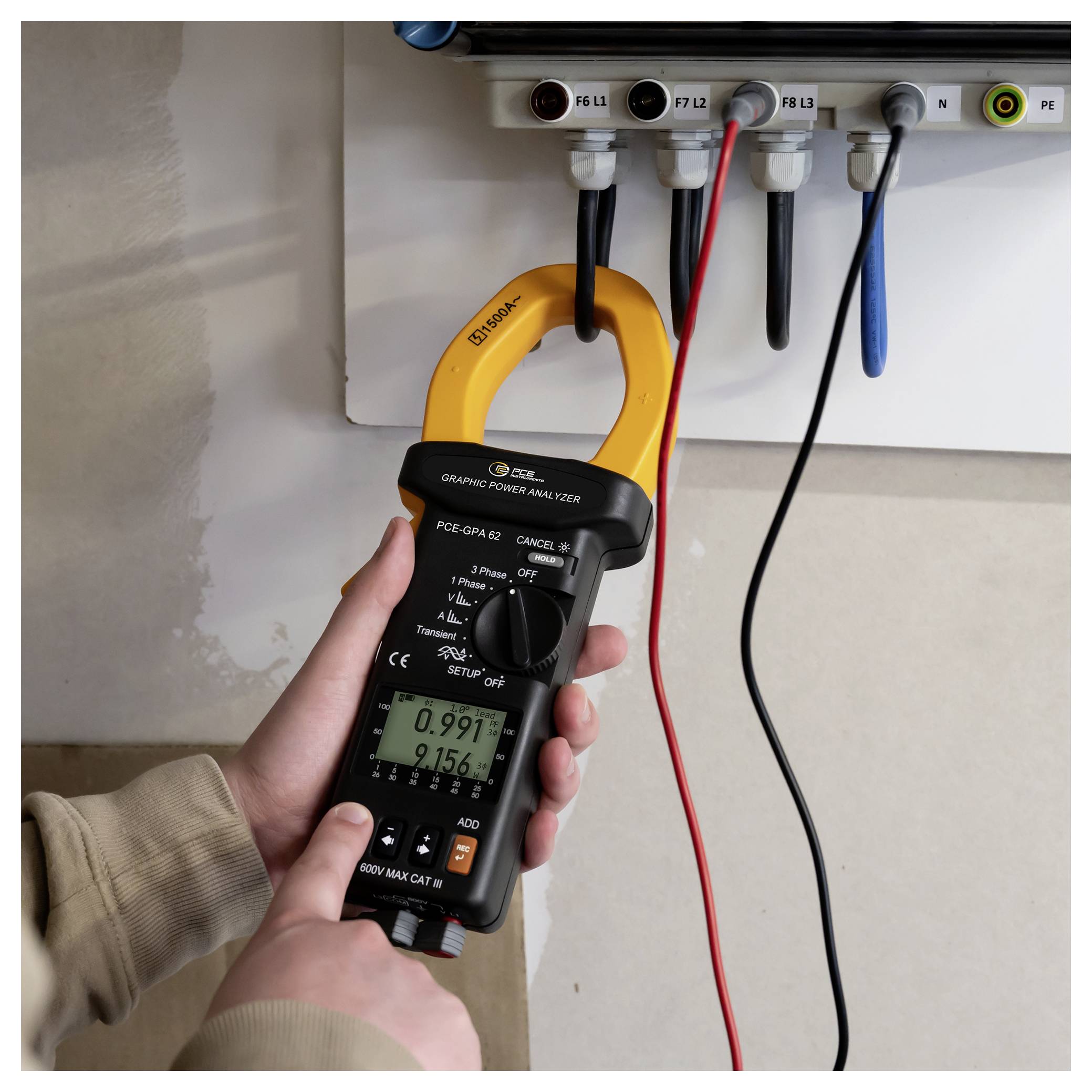 Tragbares Zangenmessgerät zur Messung des elektrischen Stroms in einem Schaltschrank, mit an Schaltungsklemmen angeschlossenen Messleitungen und einer sichtbaren digitalen Anzeige.