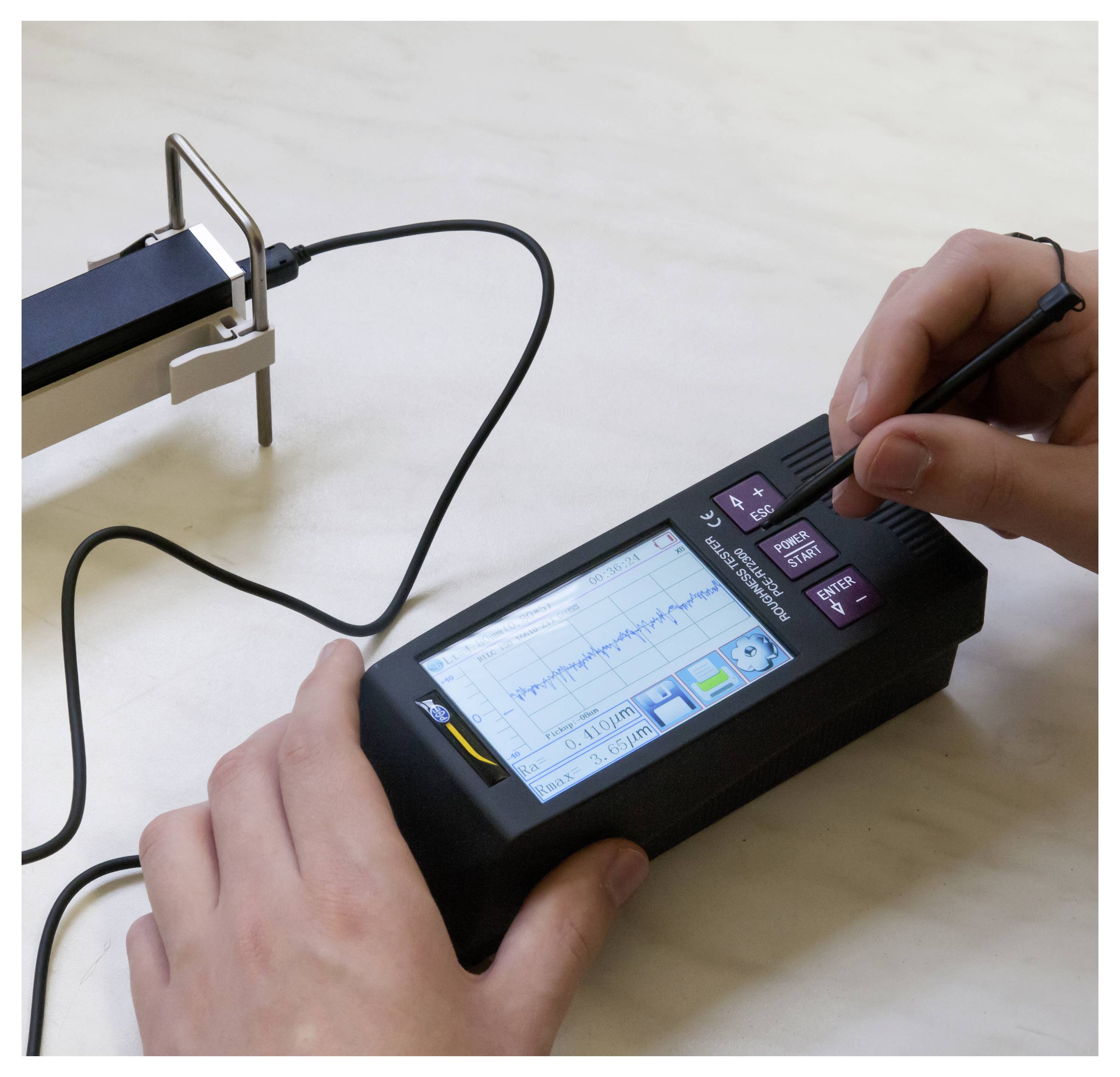 Hände halten ein tragbares Gerät mit einem Stift, während eine mit einem Kabel verbundene Graphikanzeige einen in der Nähe befindlichen Sensor oder eine Sonde anpasst.