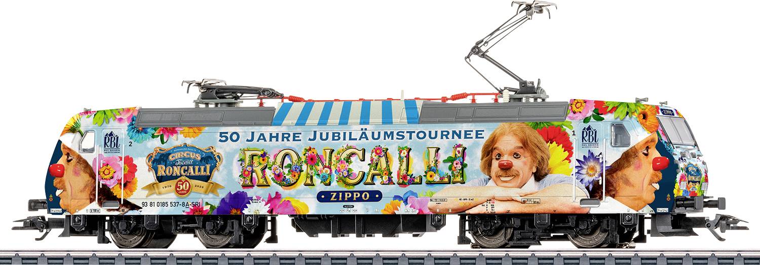 Bunte elektrische Lokomotive mit blumigem 'Roncali' Jubiläumsdesign, Text '50 Jahre Jubiläumstournee' und einem Hundeporträt auf der Seite.