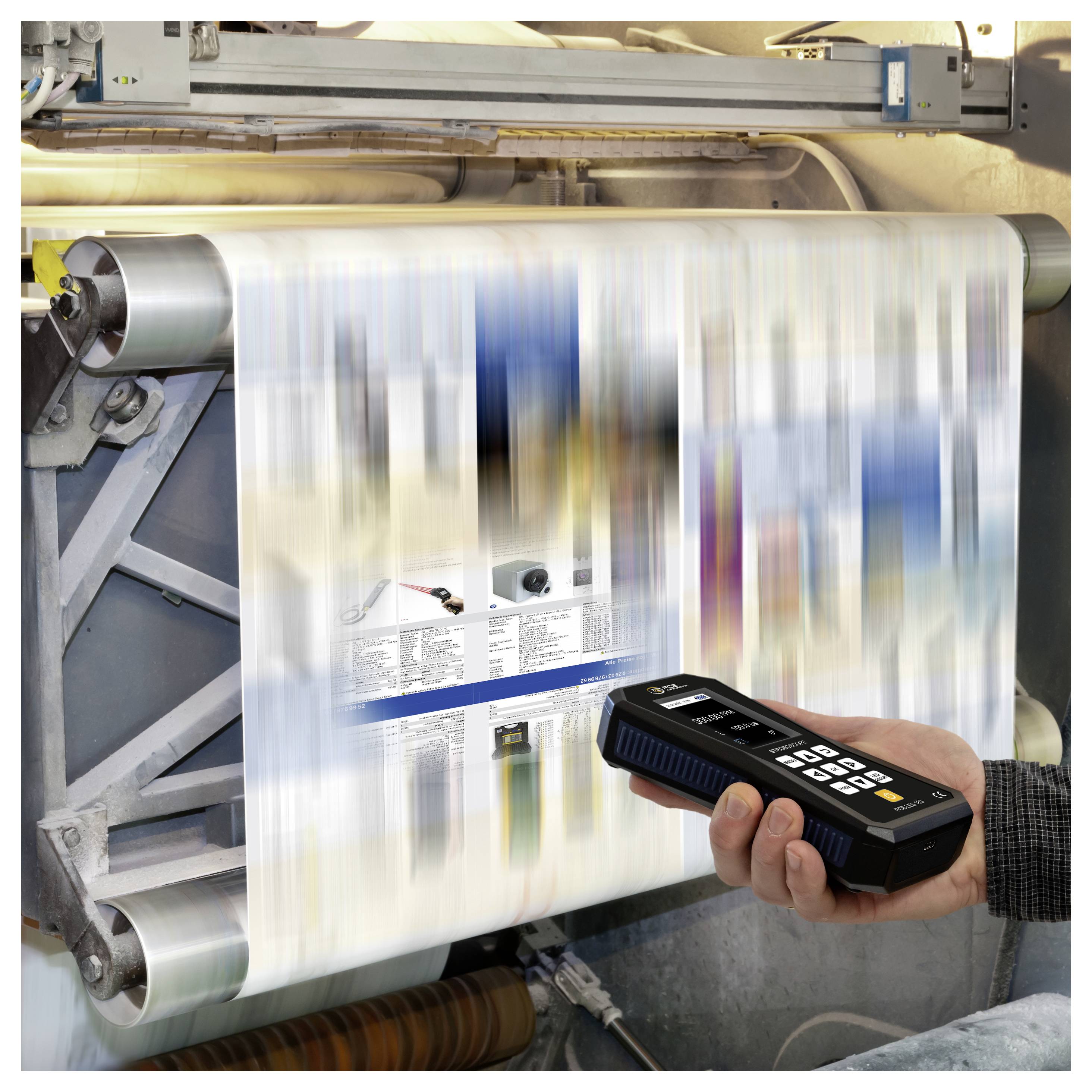 Tragbarer Scanner inspiziert eine sich schnell bewegende Druckrolle auf einer Industriemaschine, wobei die Seite durch die Bewegung unscharf ist.