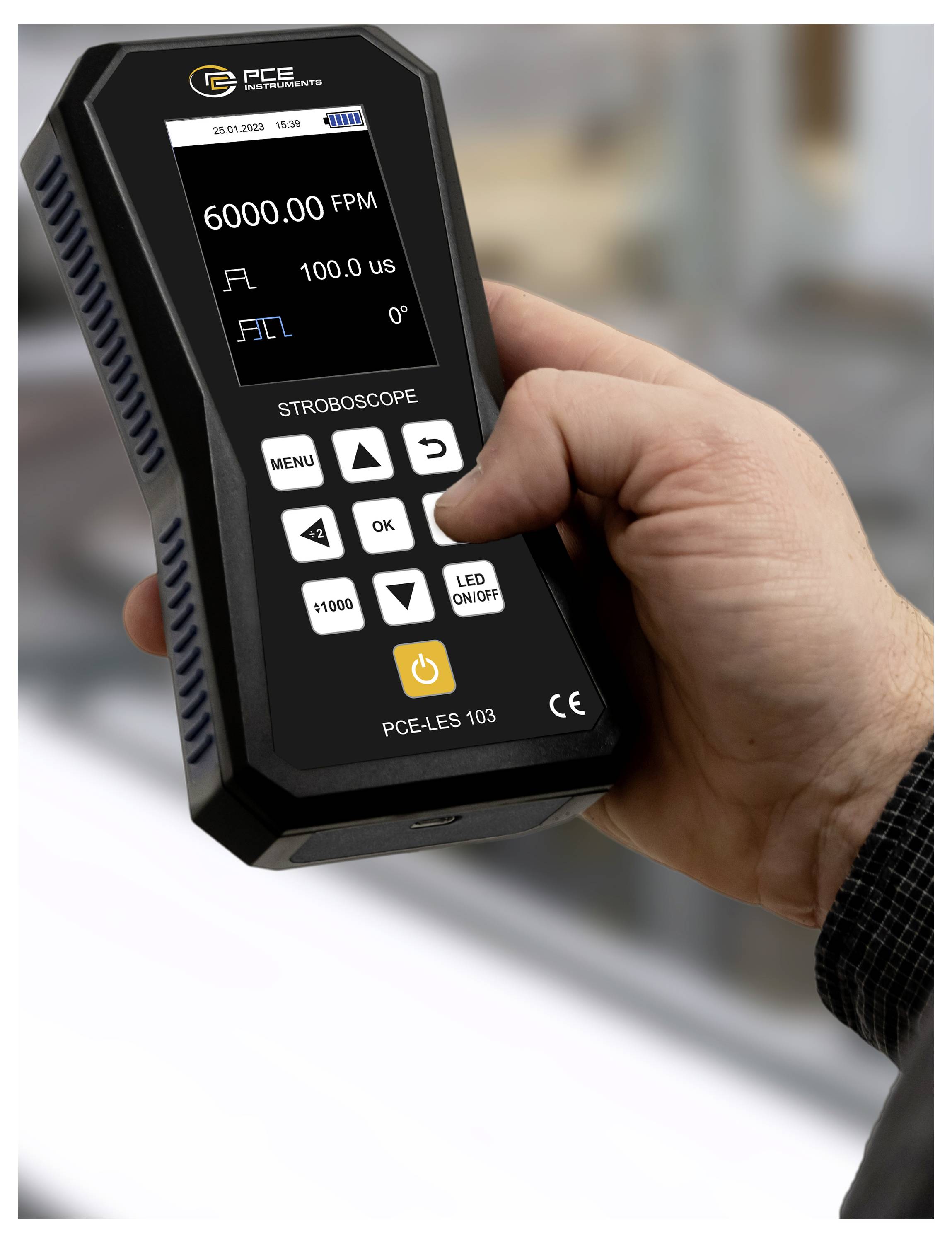 Hand hält ein PCE-Stroboskopgerät, das auf seinem Bildschirm 6000,00 FPM, 100,0 µs und 0° anzeigt.