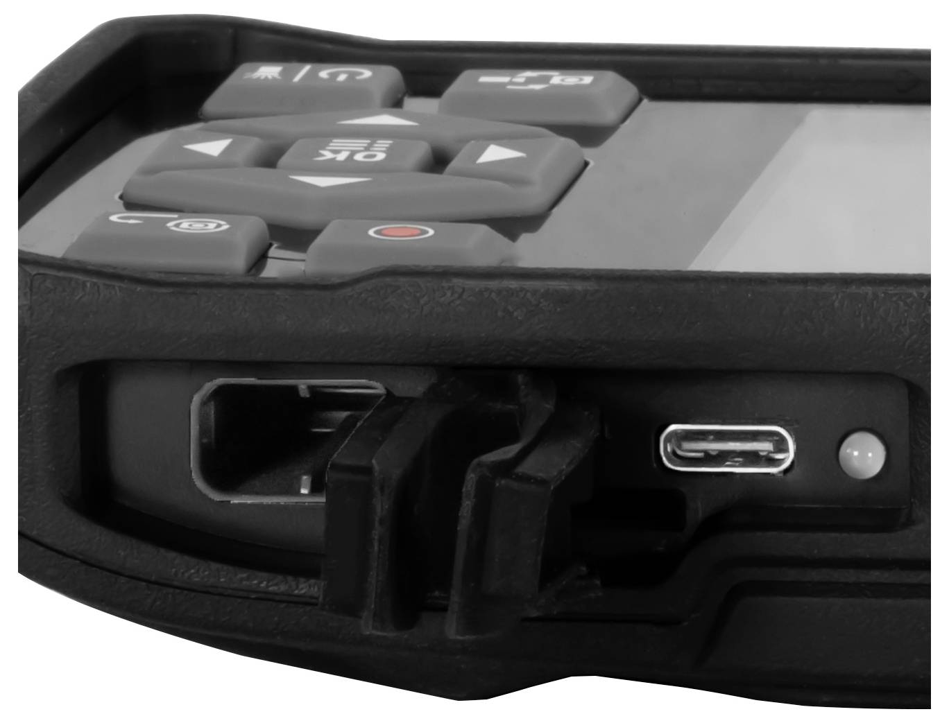 Nahaufnahme eines robusten elektronischen Geräts mit Steuertasten oben und einem USB-C-Ladeanschluss mit angeschlossenem Stecker.