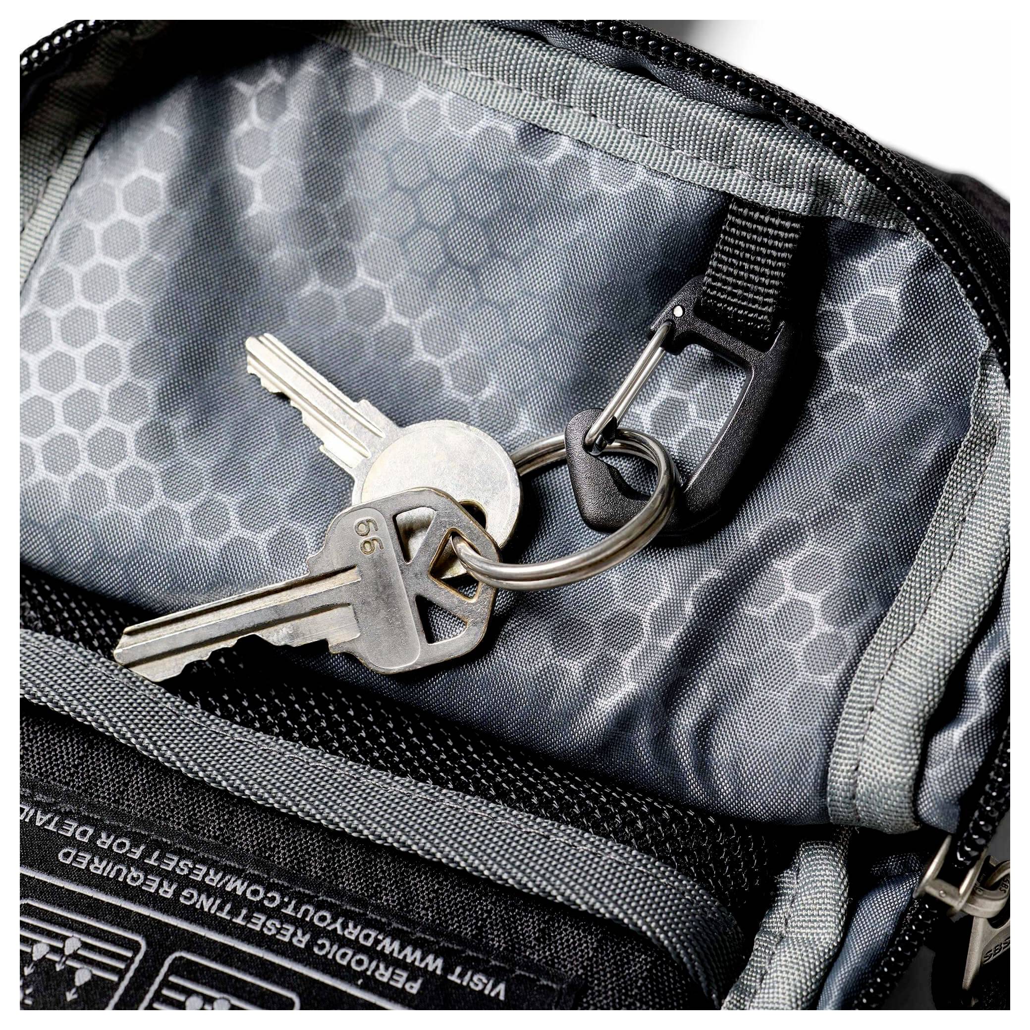 Nahaufnahme von Schlüsseln, die an einem Reißverschlussschieber in einer grauen Rucksacktasche befestigt sind.