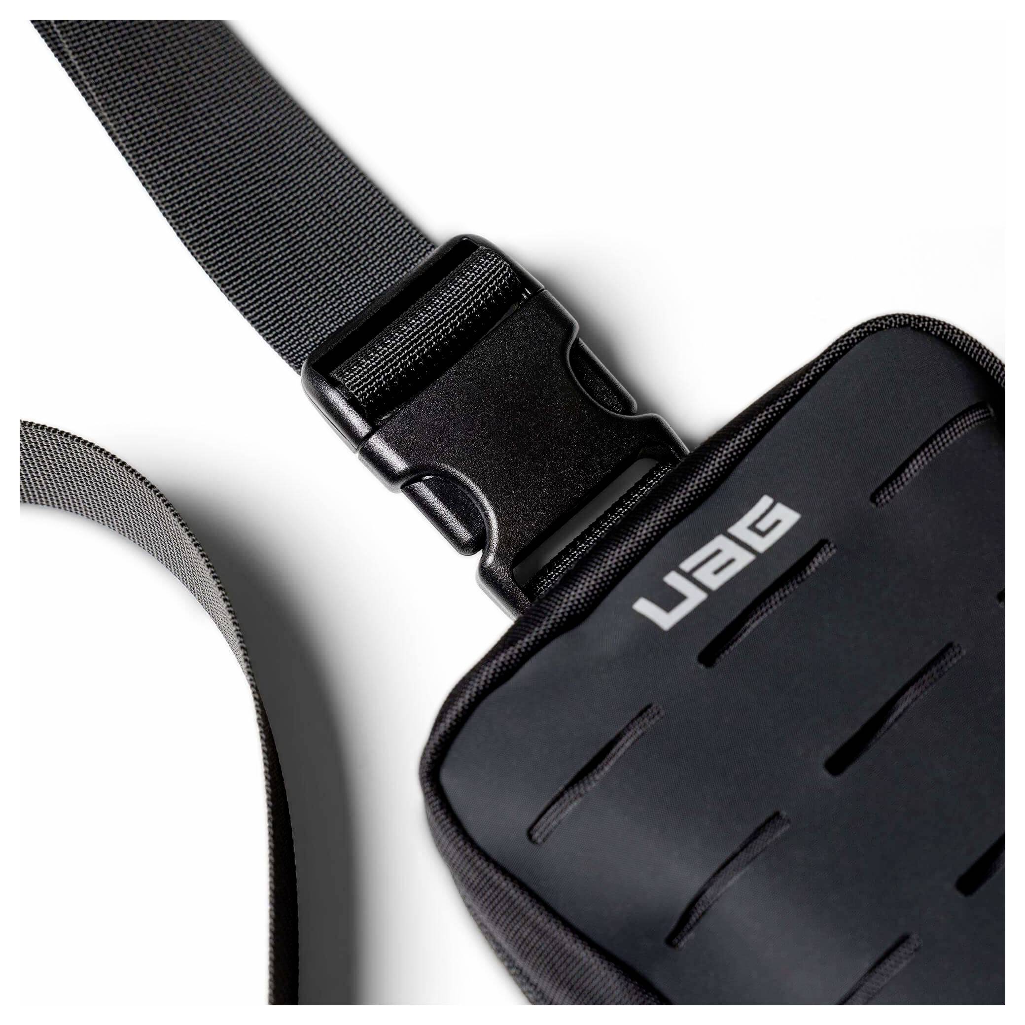 Schwarzer UAG-Riemen und Schnalle, befestigt an einer robusten schwarzen Tasche oder einem Gehäuse auf weißem Hintergrund.