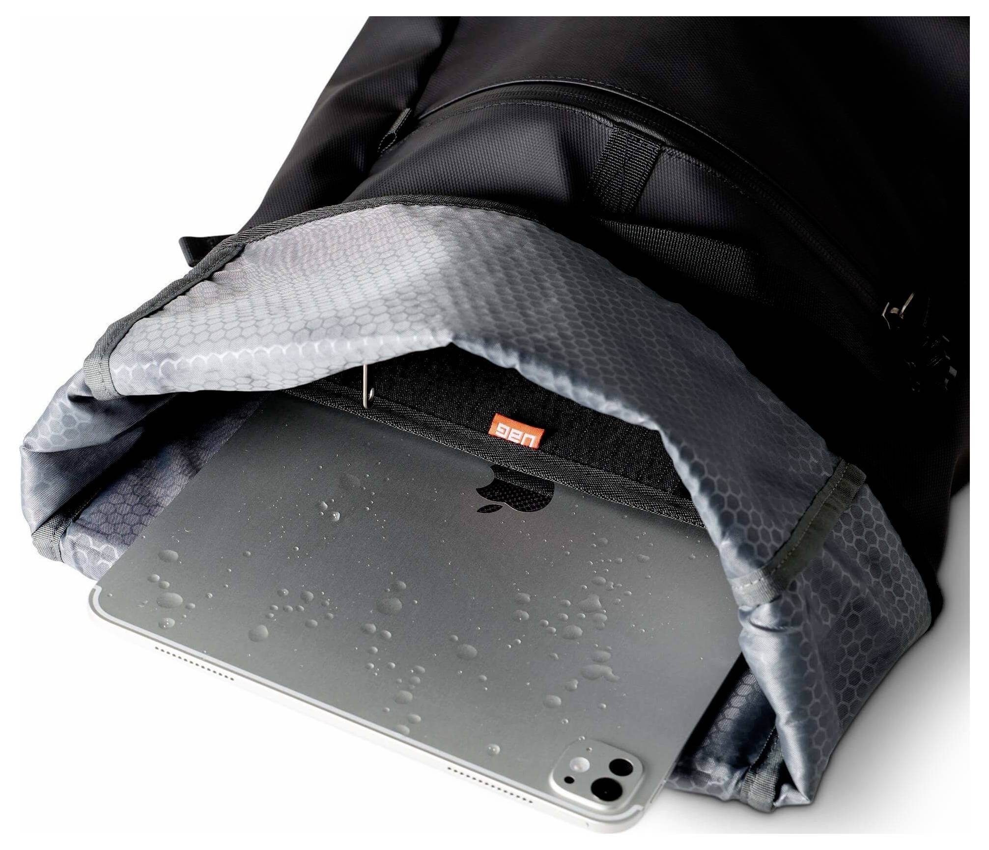 Tablet teilweise in einer schwarzen Tasche mit einer grauen gepolsterten Klappe, mit Wassertropfen auf der Tablet-Oberfläche.