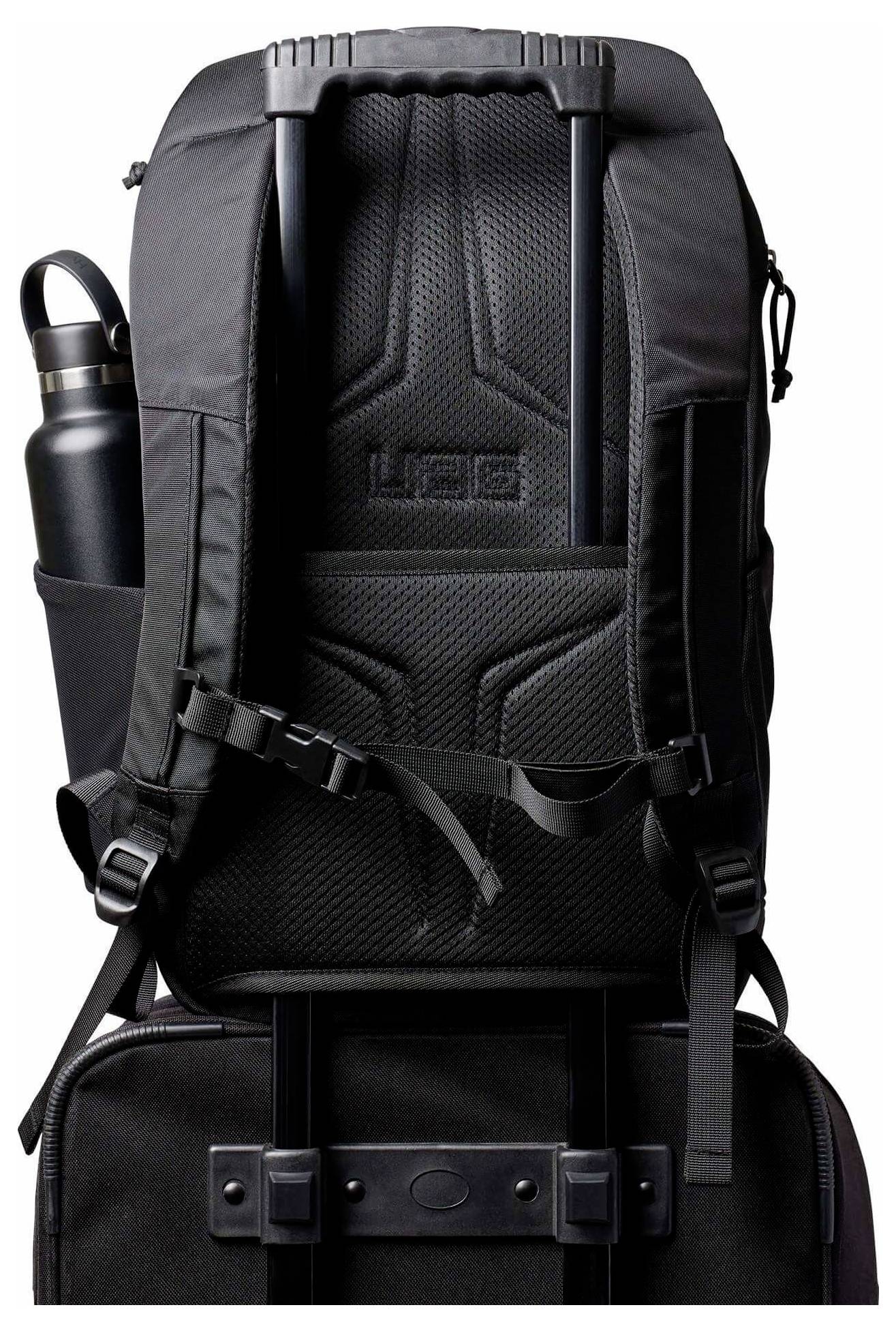 Schwarzer UGG-Rucksack mit gepolsterten Trägern, vorderen Kompressionsgurten, seitlicher Wasserflaschentasche und einer unteren angebrachten Tasche oder einem Etui.