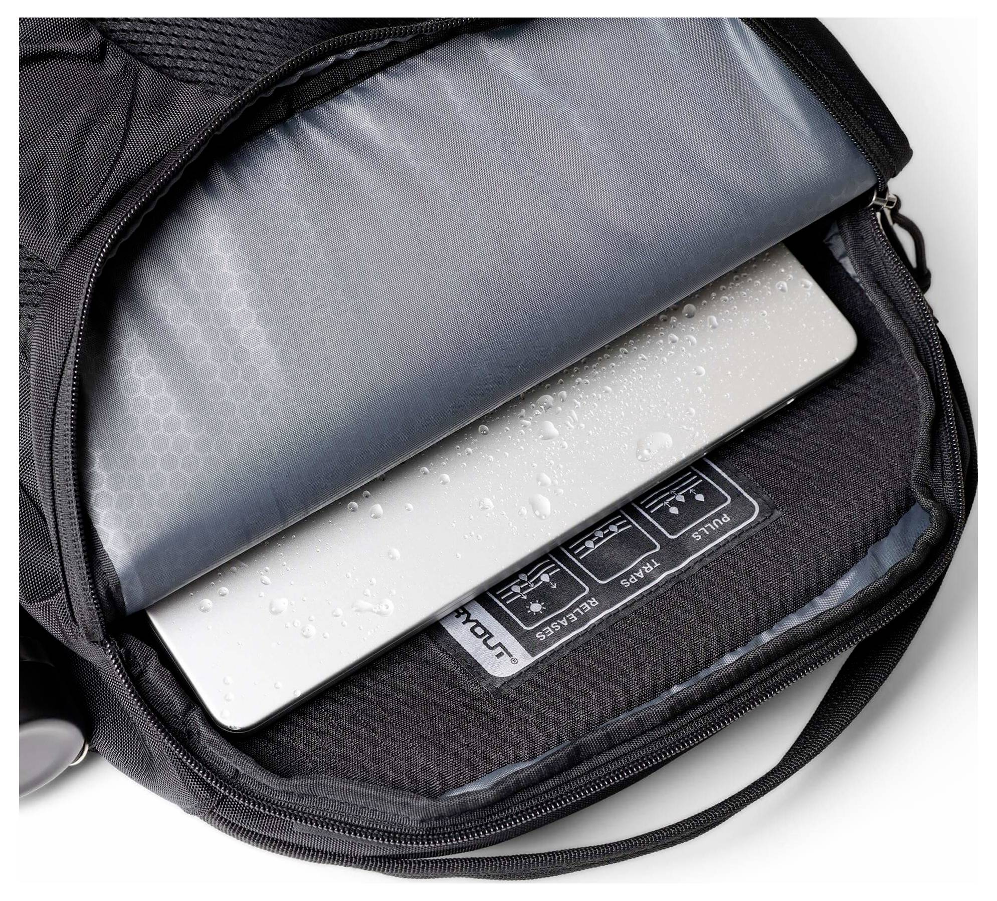 Offene Laptop-Schutztasche mit einem silbernen Laptop, der teilweise eingefügt ist, mit Wassertropfen und einem gepolsterten Schutzinneren.