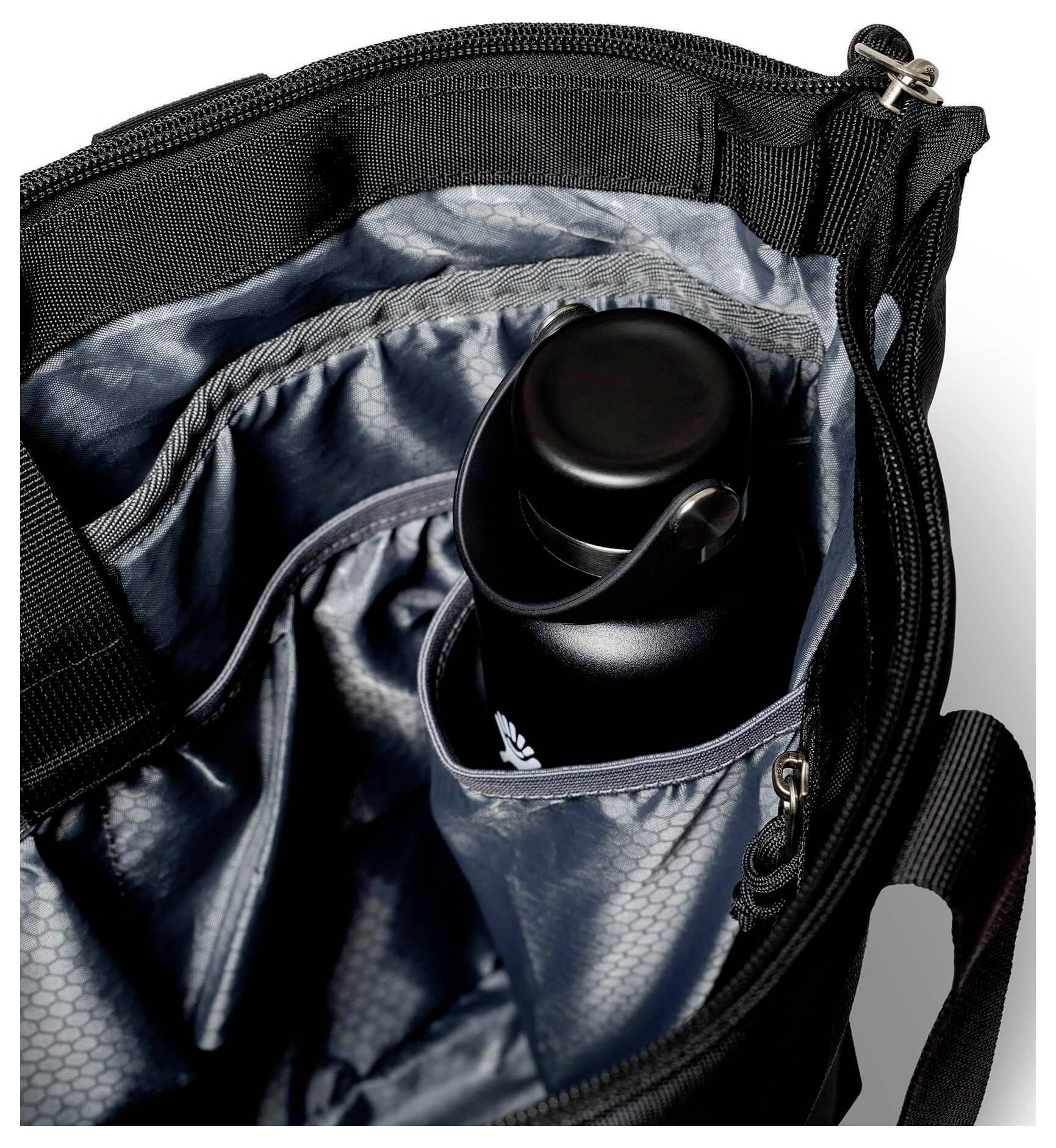 Offene schwarze Tasche von innen mit einer gepolsterten Seitentasche, die eine schwarze Wasserflasche hält.