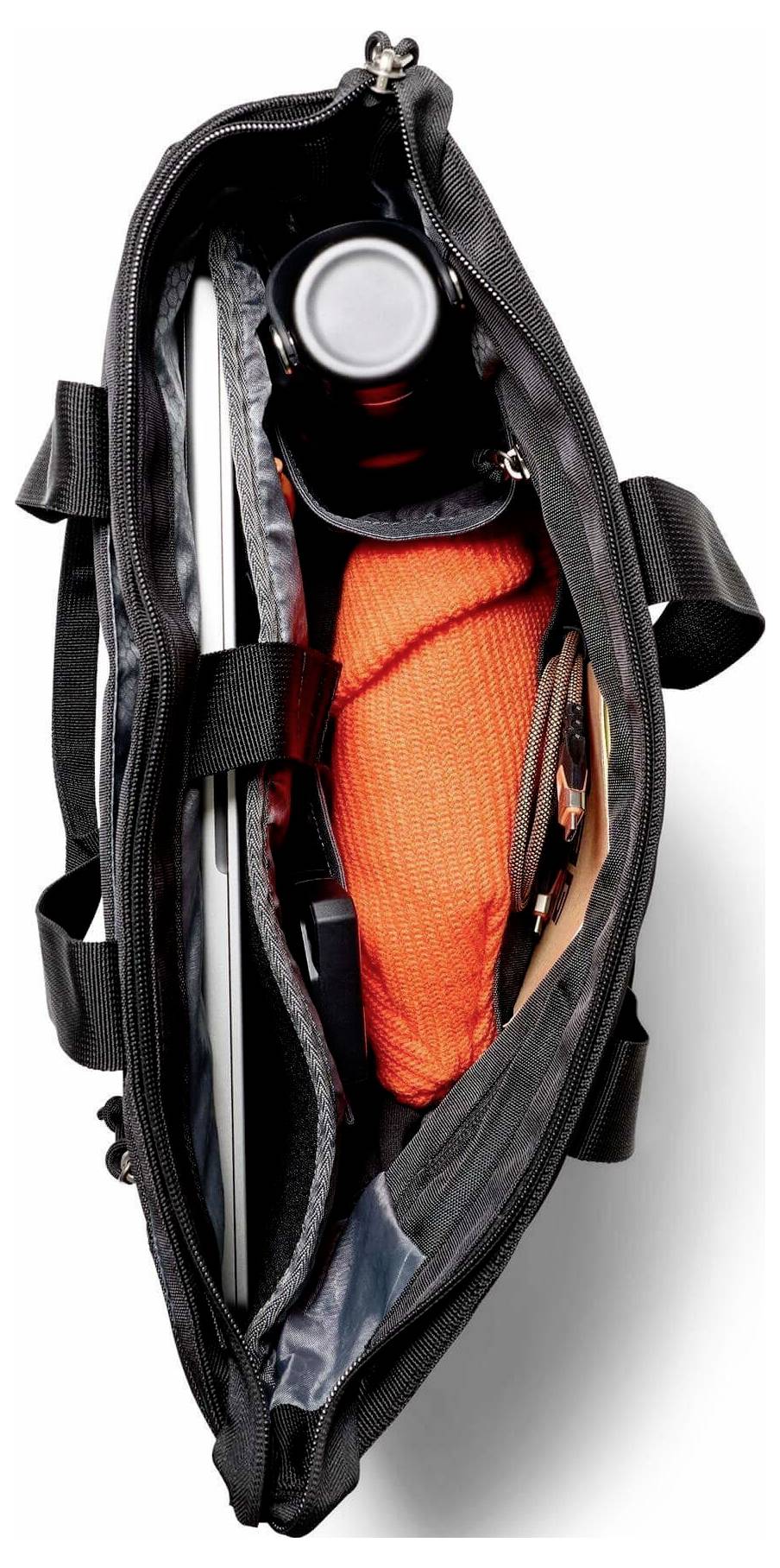 Offene schwarze Tasche mit einer aufgerollten orangefarbenen Gegenstand und einem kleinen Behälter mit silbernem Deckel im Inneren.