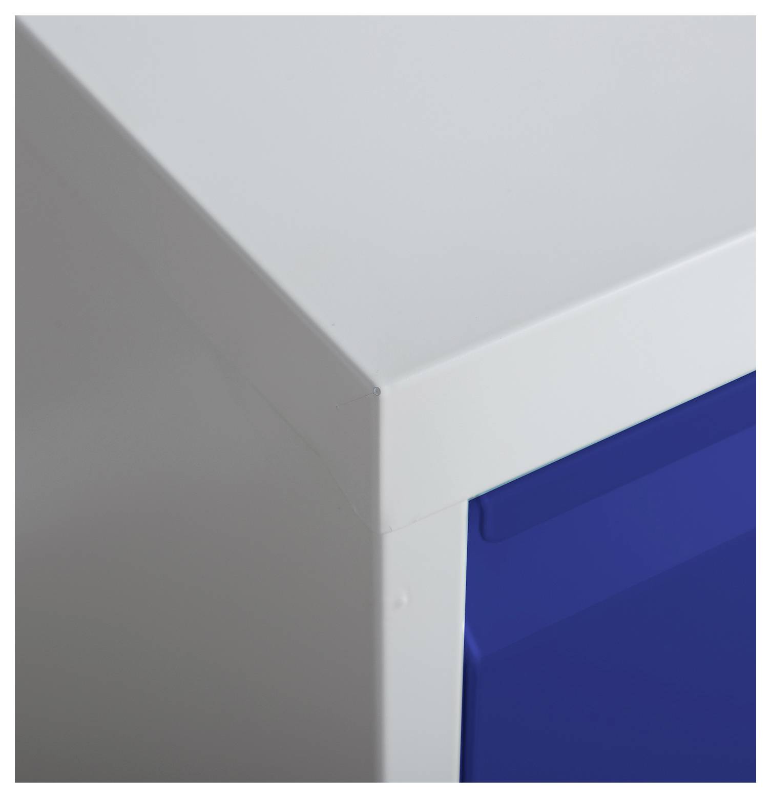 Nahaufnahme einer Ecke eines weißen Schranks oder einer weißen Box mit einer blauen Tür oder einem blauen Panel, das die Kante und Nahtdetails zeigt.