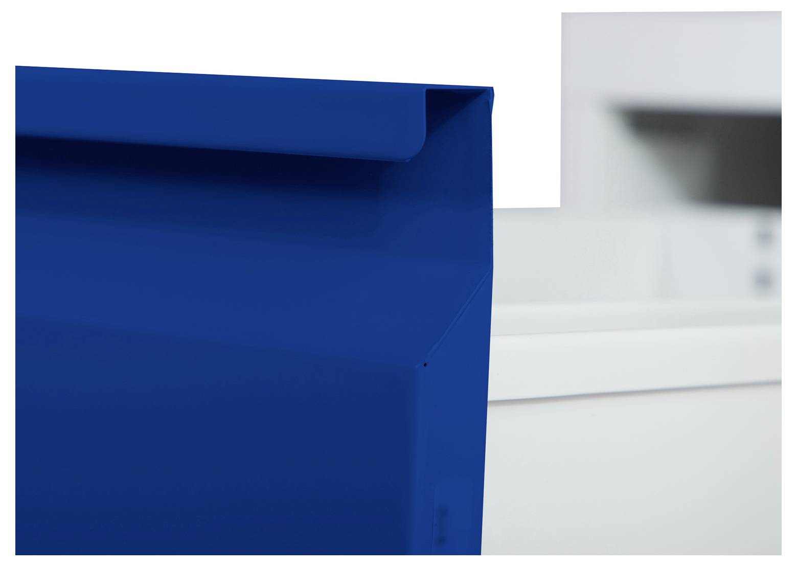 Nahaufnahme eines blauen Dokumentenordners oder Ringbuchs im Vordergrund, mit einem unscharfen weißen Bürodrucker oder Kopierer dahinter.