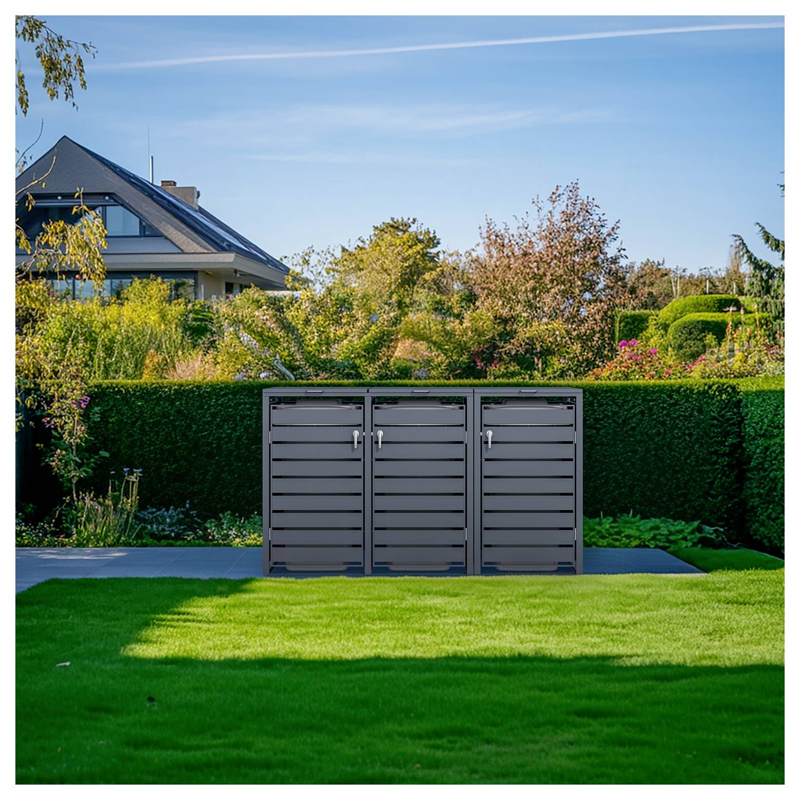 Ein grauer dreitüriger Außenlagerungsschrank steht auf einer Terrasse in einem gestalteten Hinterhof mit Rasen, Hecken, Bäumen und einem Haus im Hintergrund.