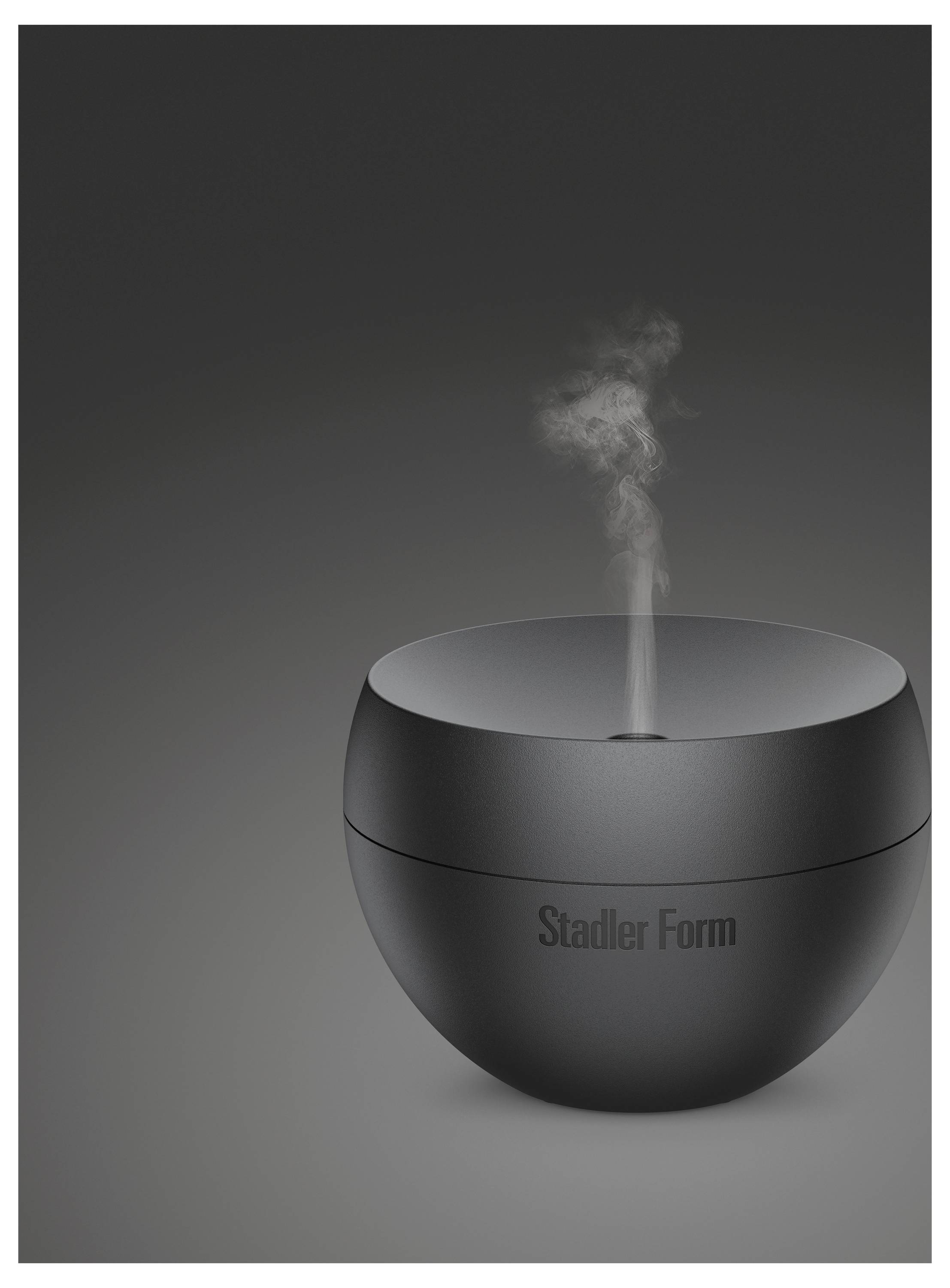 Schwarzer Stadler Form Luftbefeuchter mit aufsteigendem Nebel aus der oberen Öffnung auf grauem Hintergrund.