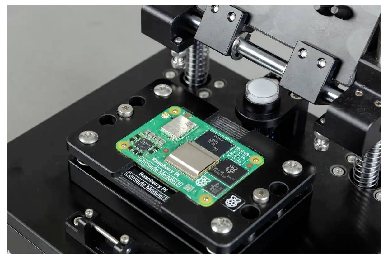 Nahaufnahme eines auf einer schwarzen Testvorrichtung oder Robotereinrichtung mit Federn und Metallklammern montierten Raspberry-Pi-Moduls.