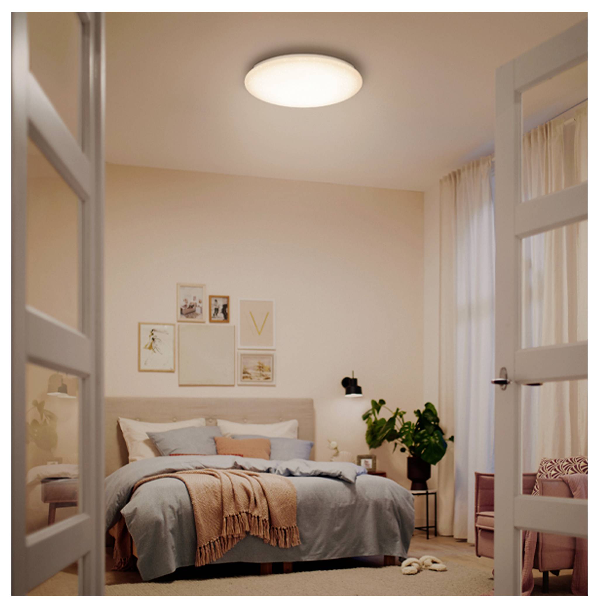 Helles minimalistisches Schlafzimmer mit einem gemachten Bett, Wandkunst, einer Pflanze auf dem Nachttisch, Vorhängen und offenen Flügeltüren, fotografiert von der Tür aus.