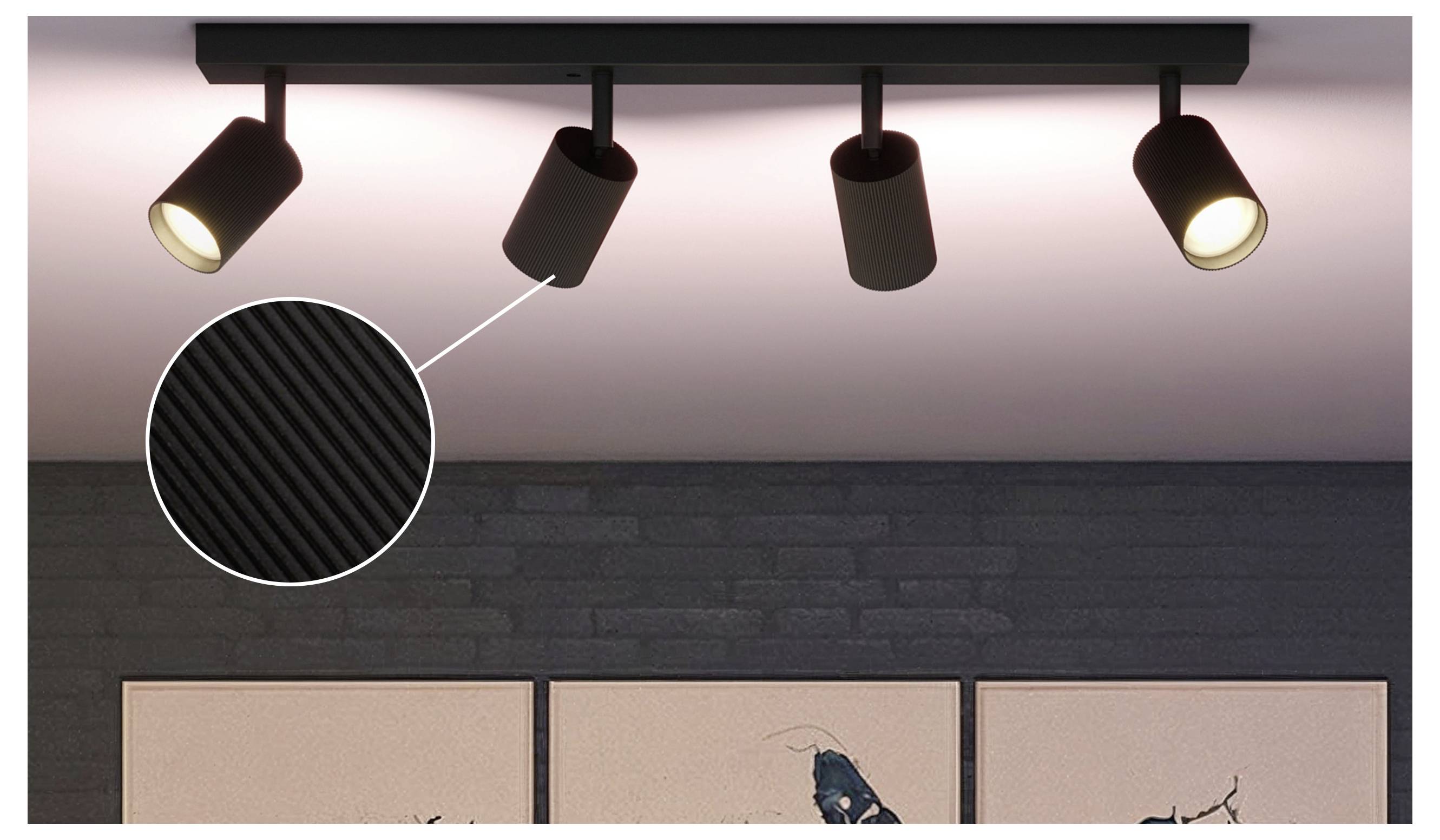 Schienensystem mit vier verstellbaren Spotlights an einer Deckenleiste, die eine Wand und Kunstwerke darunter ausleuchten.