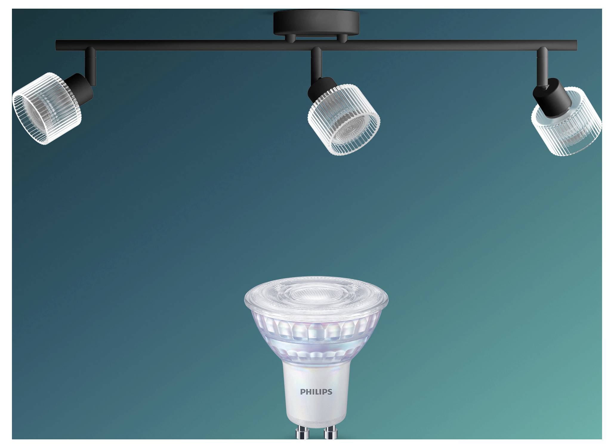 Drei Deckenspotlights beleuchten eine Philips LED-Spotlightbirne vor einem blaugrünen Hintergrund.
