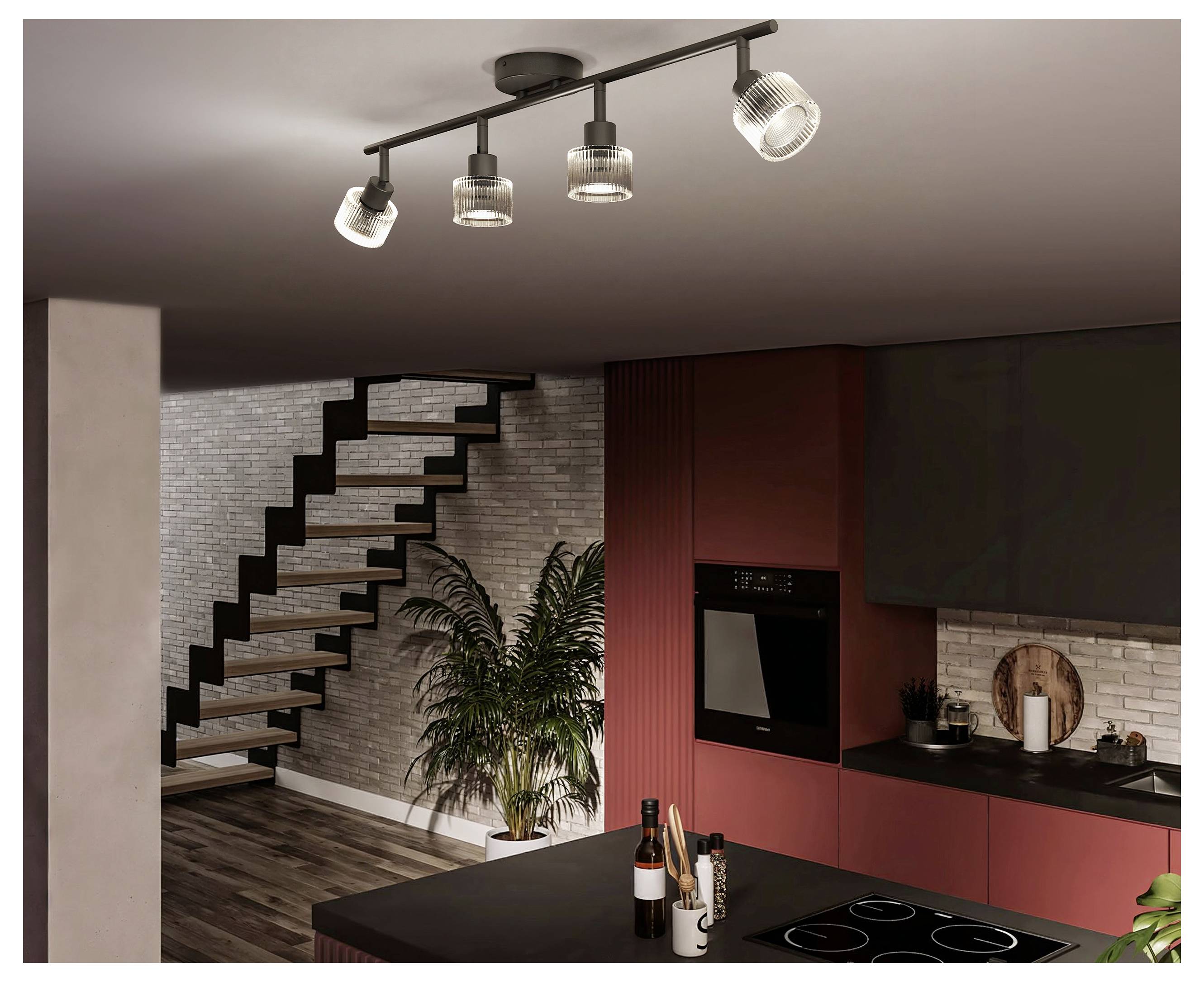 Modernes Kücheninterieur mit roten Schränken, schwarzer Insel, Treppe, Topfpflanze und Deckenleuchten an der Schiene.