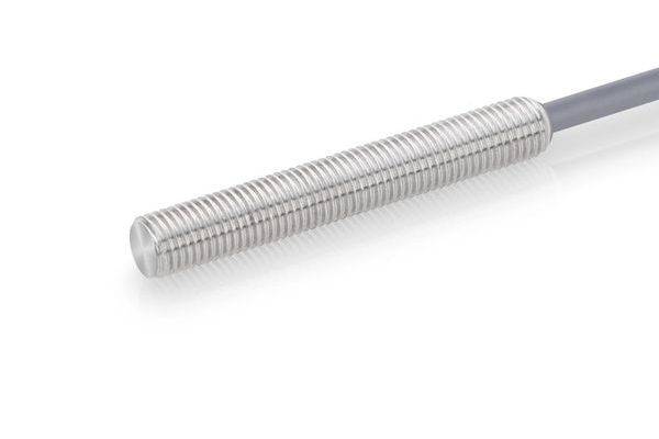 Nahaufnahme einer silbernen Metallsonde mit Gewinde in zylindrischer Form, die an einem Kabel befestigt ist, vor einem weißen Hintergrund.