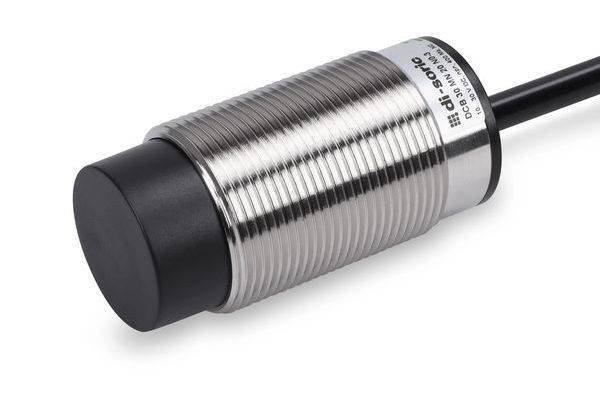 Nahaufnahme eines zylindrischen metallischen induktiven Näherungssensors mit schwarzer Sensorfläche und angeschlossenem Kabel auf weißem Hintergrund.